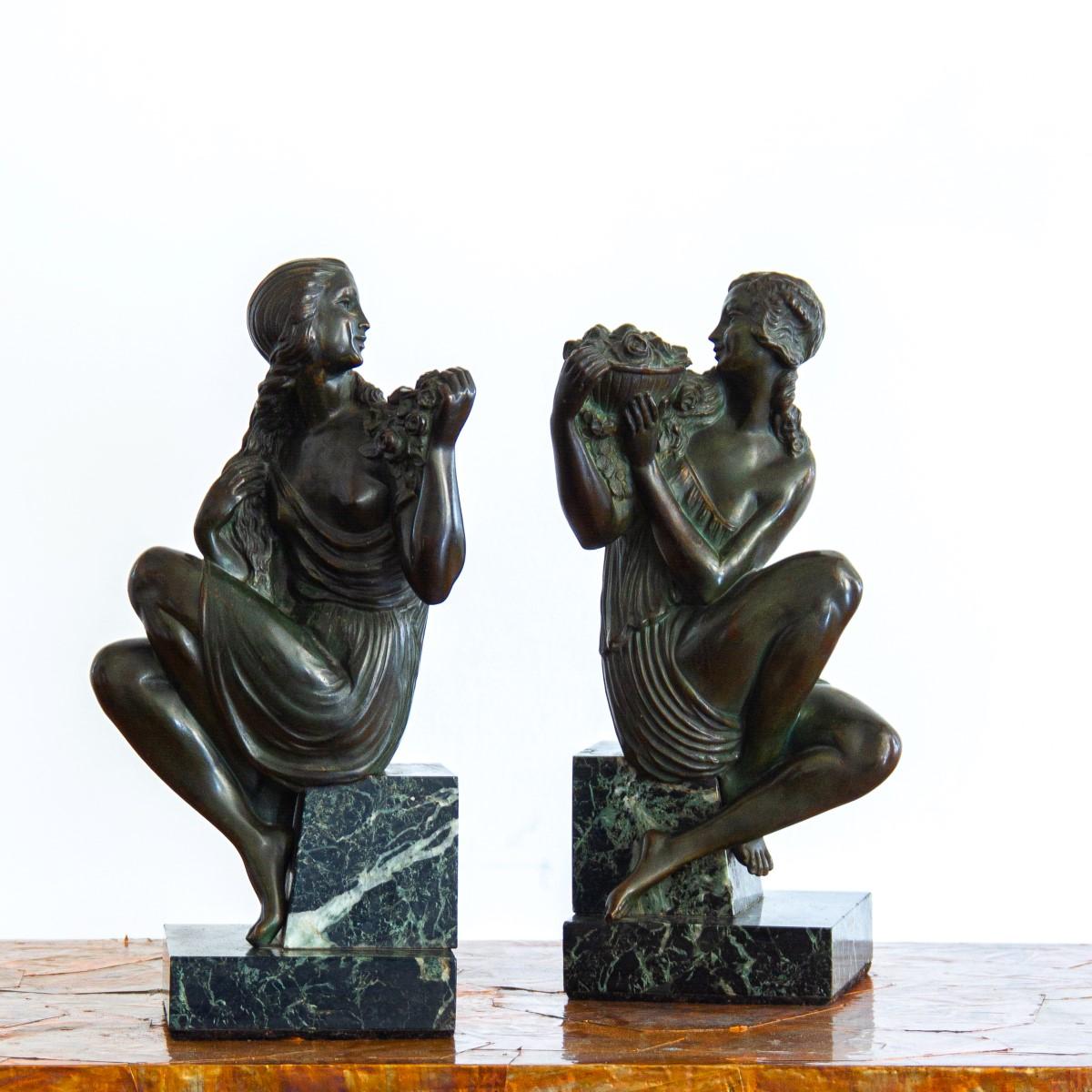 A pair of Art Deco, bronze bookends depicting neoclassical female figures looking towards each other and holding flowers, cross legged on stepped white veined black marble bases. Each base is signed 'Le Faguays', after Pierre Le Faguays. 

Pierre