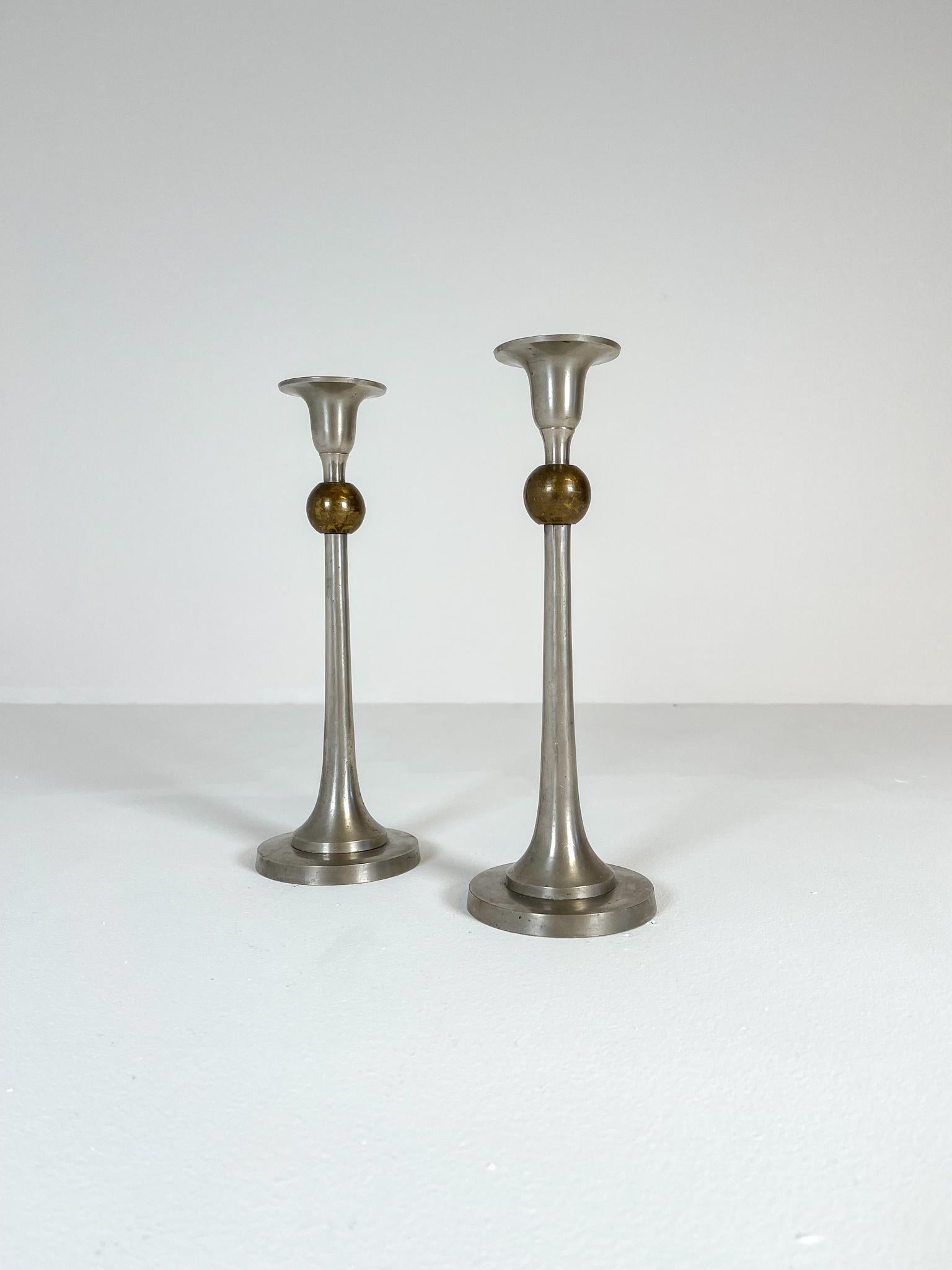 Art Deco candle holders made in pewter and brass made in Sweden during the 1930s. These ones wonderfully sculptured and crafted in a true art deco shape with the base and top in pewter with a ball in brass. 

Good vintage condition with some