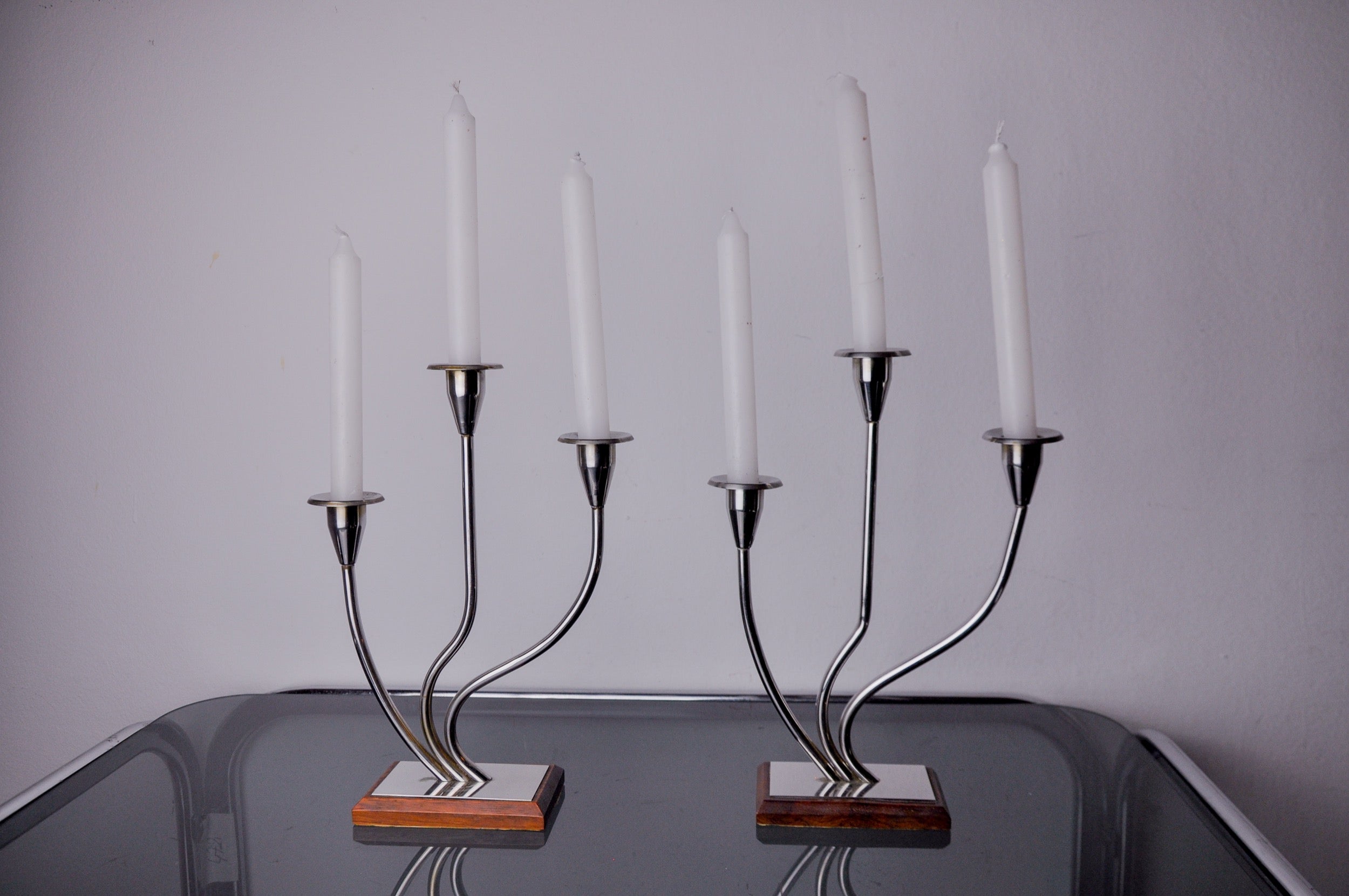 Sehr schönes Paar Art-Deco-Kerzenhalter aus Edelstahl und Palisanderholz, entworfen und hergestellt in Spanien in den 1970er Jahren. Struktur aus rostfreiem Stahl 18/8, die 3 Kerzen aufnehmen kann. Hervorragendes Designobjekt, das Ihr Interieur