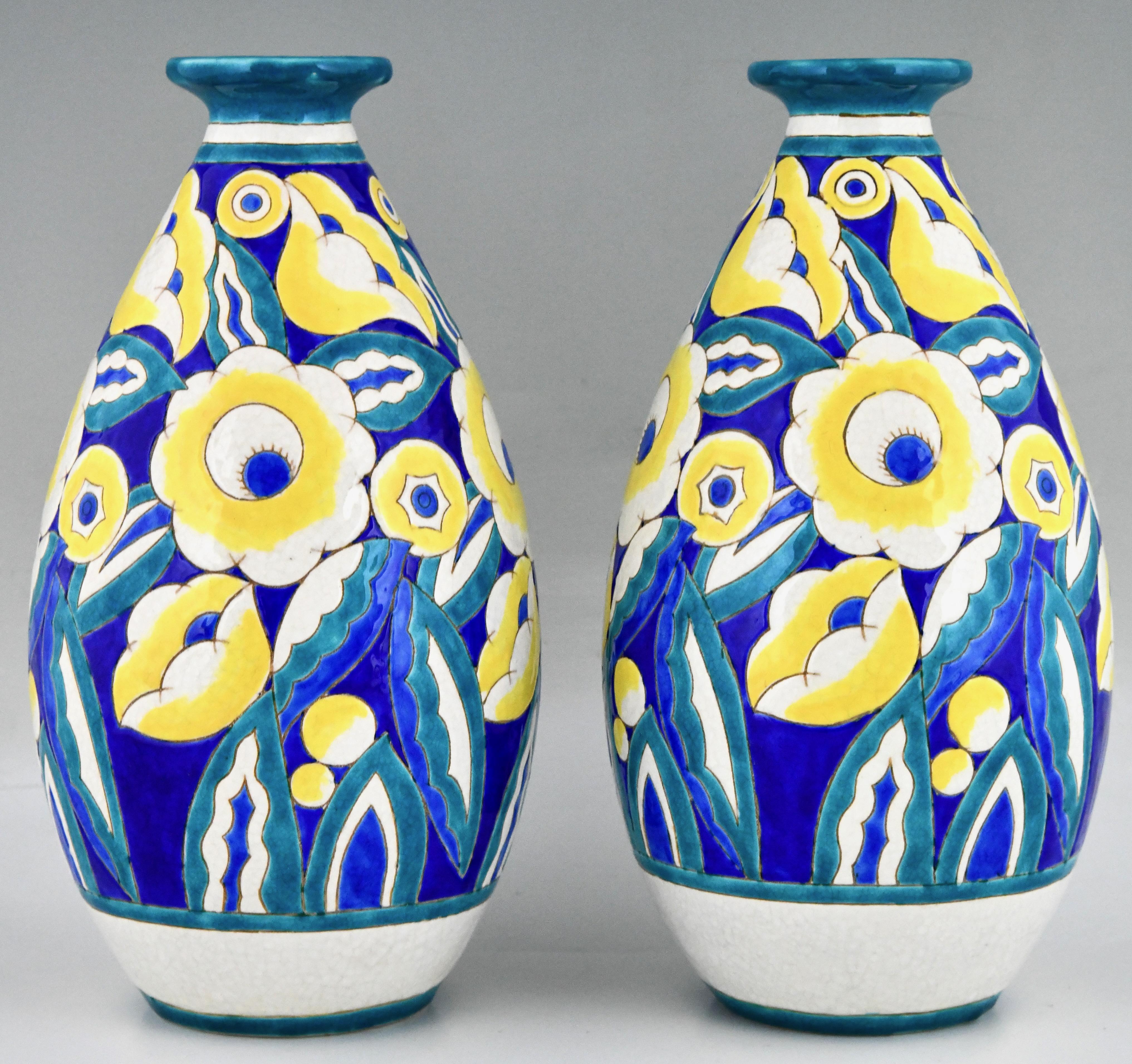 Paar Keramikvasen mit Blumen im Art déco-Stil von Keramis, Belgien.
Türkisfarbene, blaue, weiße und gelbe Craquelé-Keramik. 
Mit dem Keramis-Stempel und der Modellnummer D1558 für das Dekor.
Markiert, 22 und 960 für die Form. 
Belgien 1932. 
Dieses