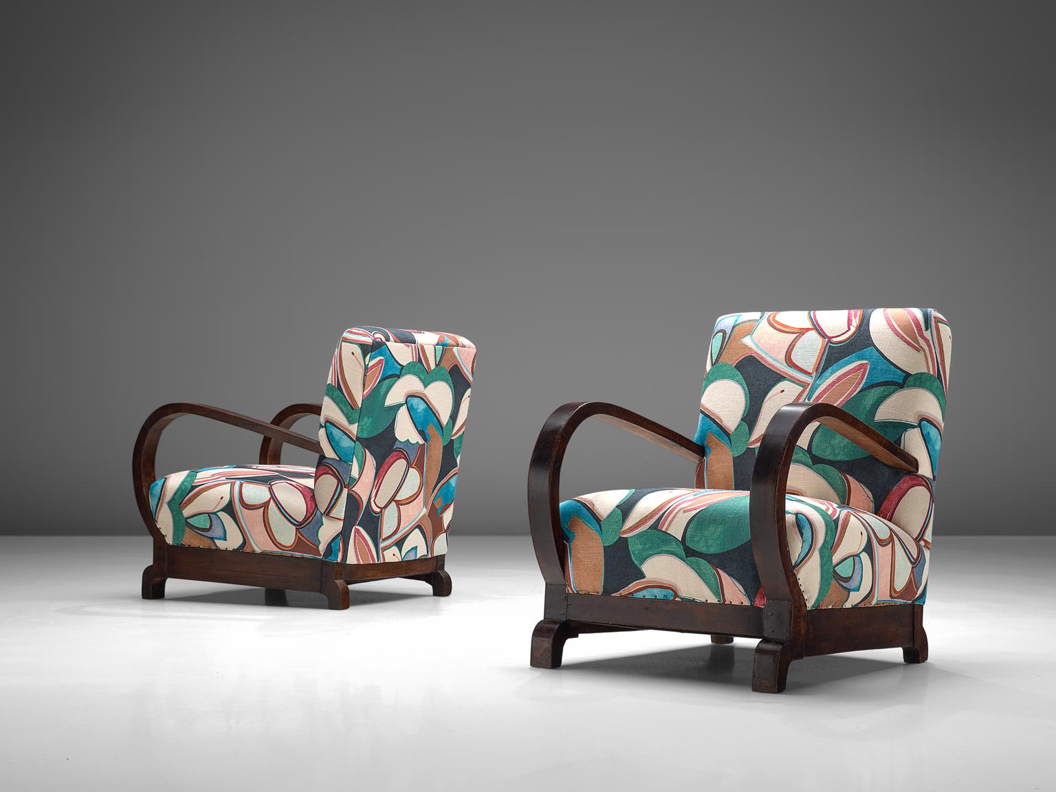 Set of two lounge chairs, floral fabric in green, blue and pink, lacquered and stained oak, Europe, 1930s. 

This extraordinary pair of chairs are customized by the experienced craftsmen in our in-house atelier. The chairs are upholstered with a