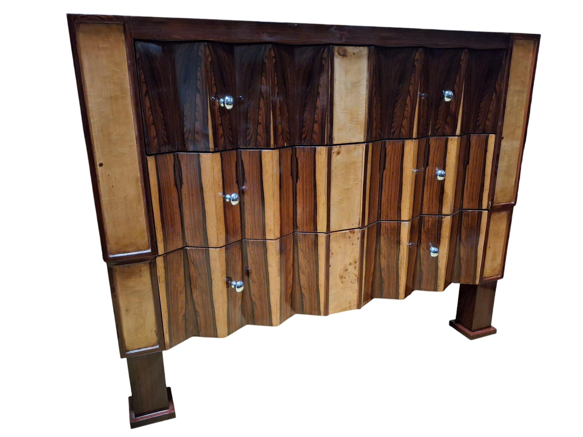 Coppia di cassettiere art déco in palissandro e legno misto, ciascuna composta da tre cassetti 
con un fregio a cassetti a zig zag, che si erge su massicce gambe a blocco con piedi quadrati.