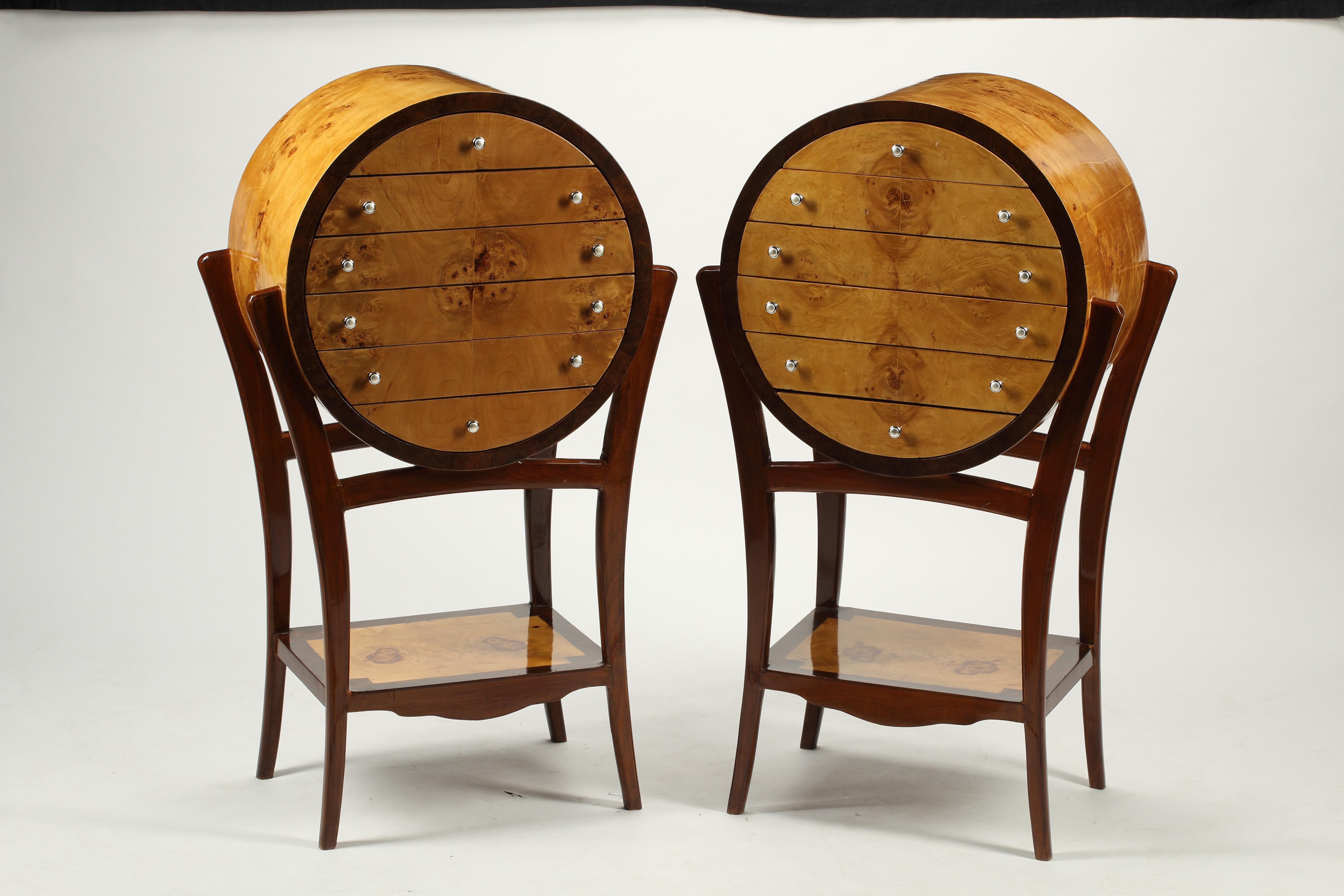 Una coppia di cassettiere in stile Art Déco. Una coppia altamente decorativa di cassapanche in legno bicolore che evidenziano le venature dei legni in contrasto. La cassettiera a sei cassetti a forma di barile poggia su quattro gambe ad arco per uno