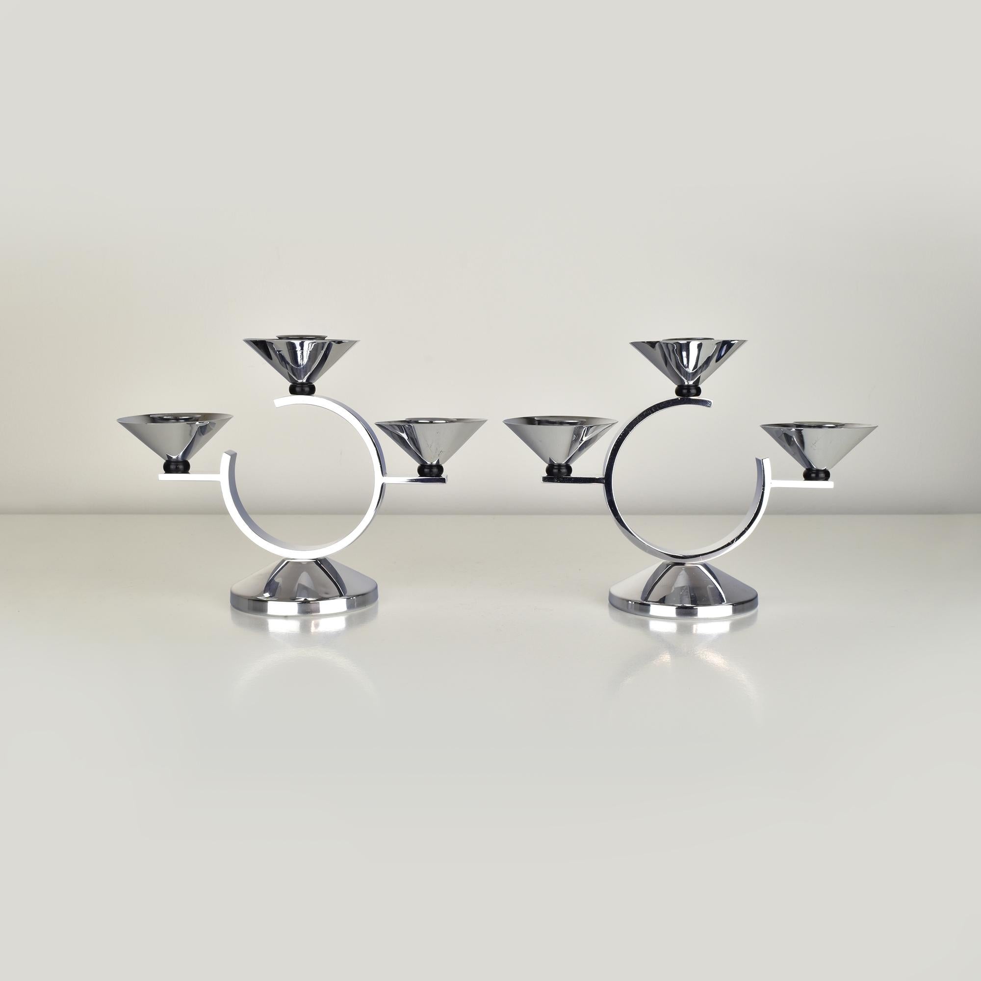 This pair of Art Deco candleholders embodies the sleek, futuristic aesthetics of the Machine Age and Modernist design movements. Crafted from polished chrome, the candleholders feature geometric, circular forms with bold, industrial lines. The