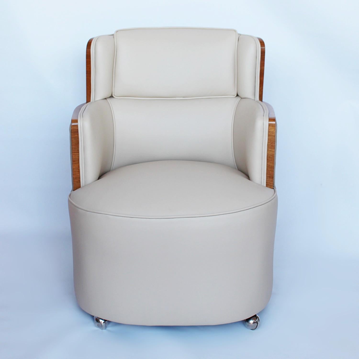 A pair of Art Deco club chairs in walnut, upholstered in cream leather with Alcantara suede backs. Later chrome wheels. 





