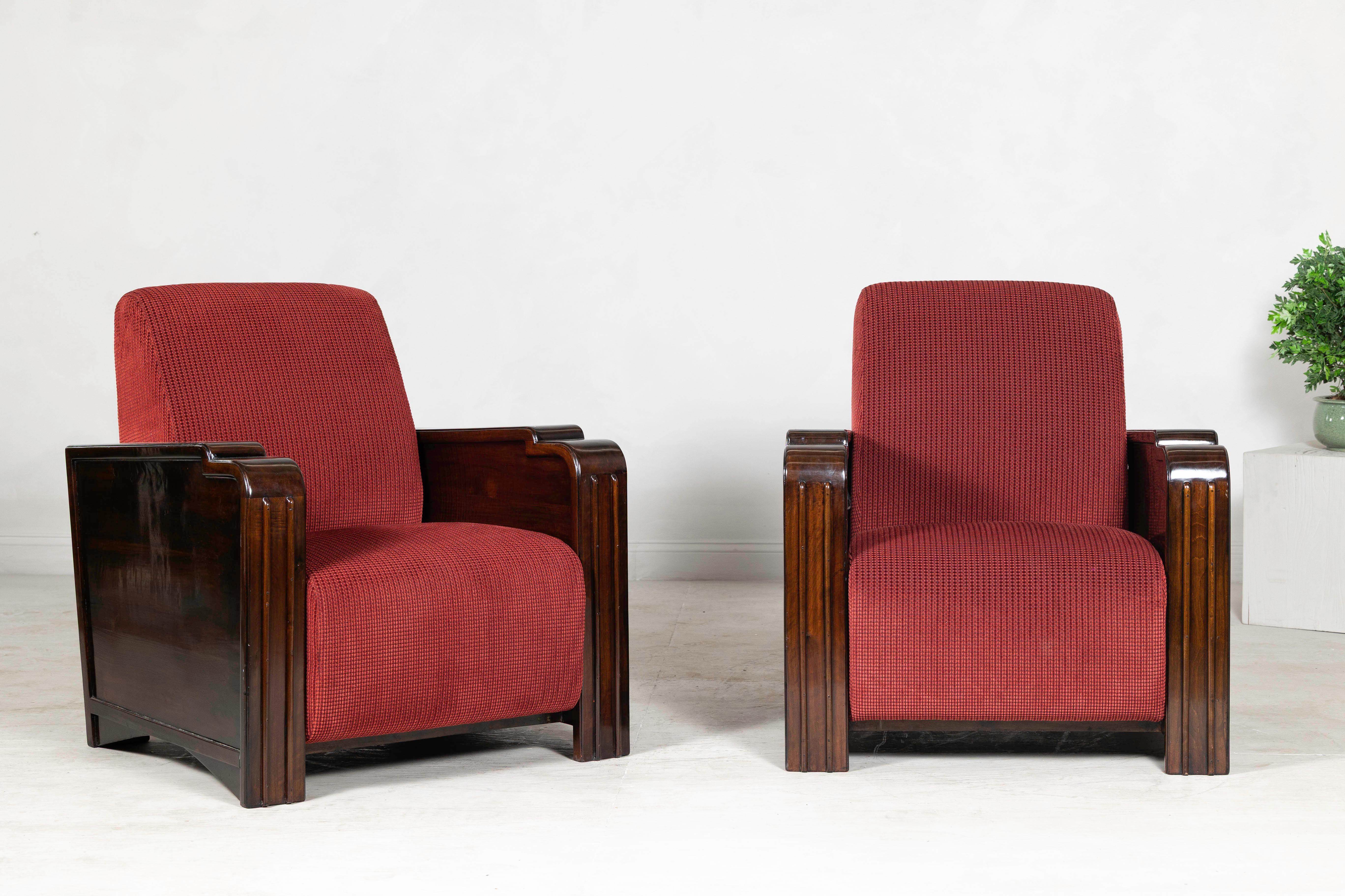 Questa coppia di sedie club Art Déco vintage offre una silhouette audace ed elegante, caratterizzata da linee scultoree e materiali caldi e raffinati. Le sedie sono caratterizzate da ampi braccioli in legno riccamente lucidato, che aggiungono una