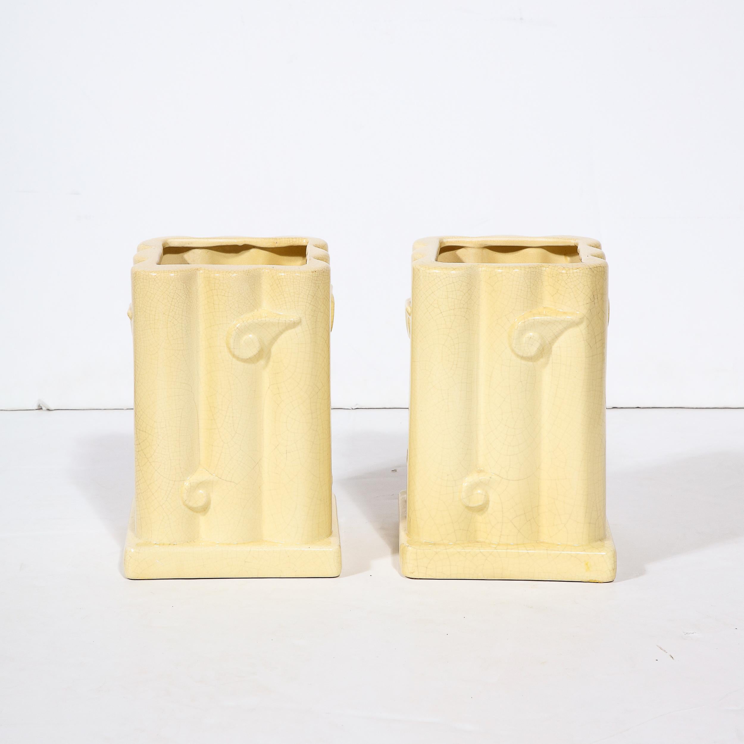 This elegant pair of Art Deco ceramic vases were realized in Belgium circa 1930. They feature rectangular volumetric bodies with square bases that cantilever beyond the perimeter of each form. The silhouettes vases are composed of columnar forms
