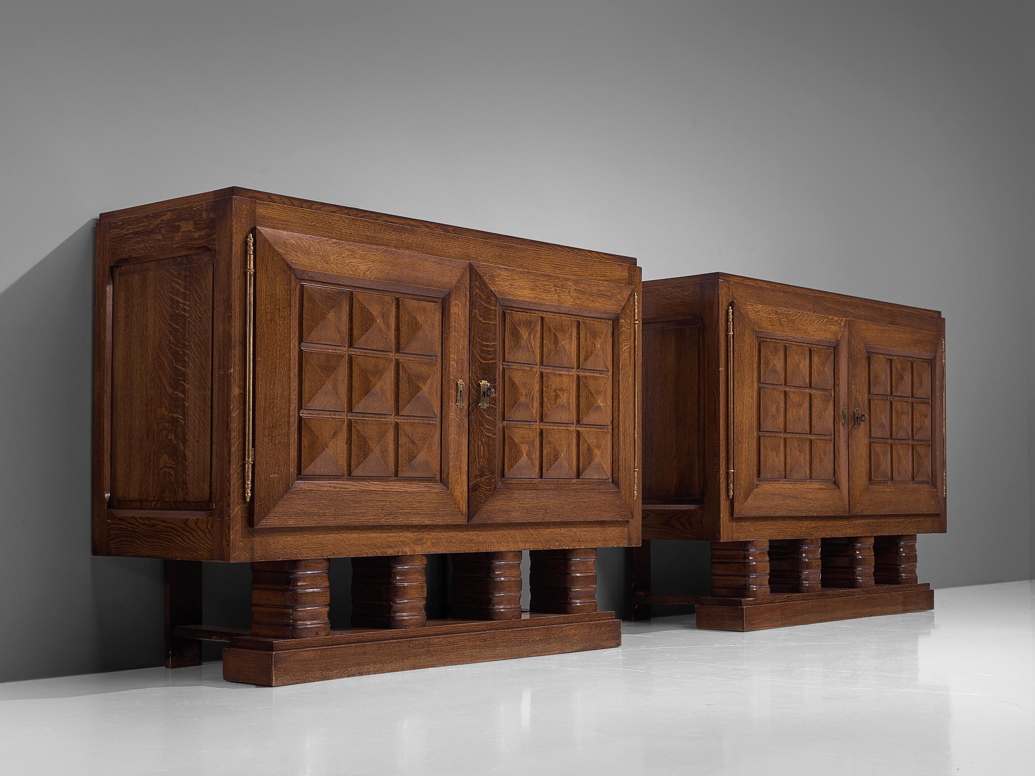 Gaston Poisson, pair of small credenzas, stained oak, France 1930s. 

Sturdy pair of identical credenzas in oak with graphical doorpanels. These sideboards are equipped with several shelves which provide plenty of storage space. The doorpanels and