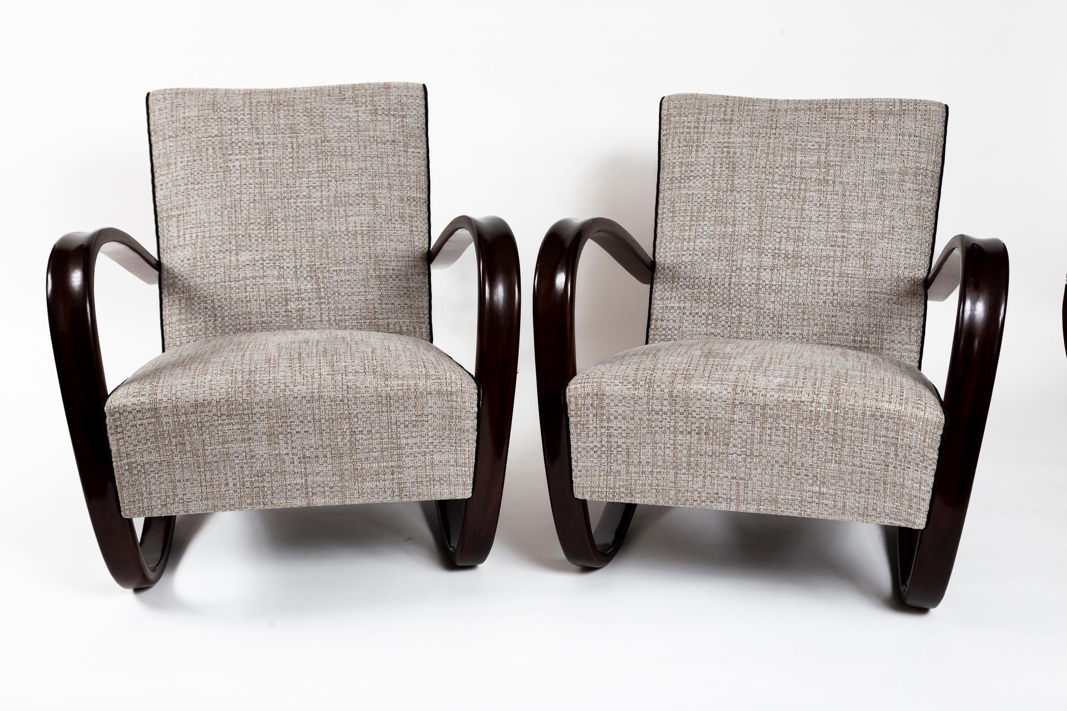 Iconic pair of lounge chairs in a dark walnut stained beechwood with a streamline design by Jindrich Halabala for UP Zavody.

Recently wood refinished in a low lustre walnut finish and reupholstered in a thick and sturdy neutral chenille woven