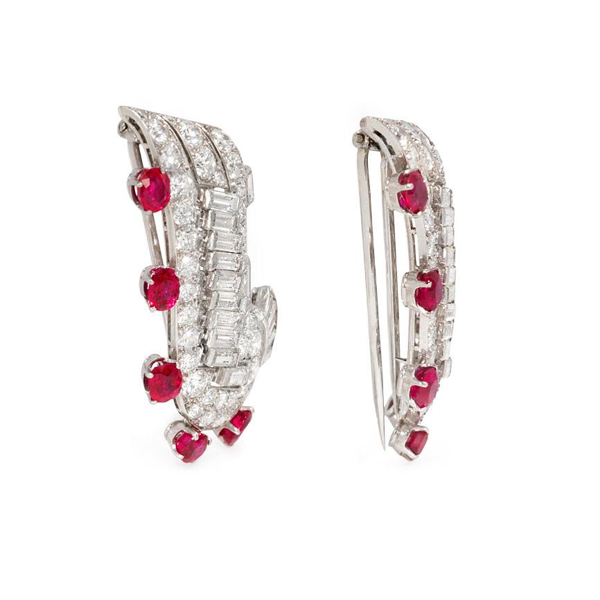 A pair of Art Deco diamond and ruby dress clips of scroll design, each clip brooch set with round and baguette diamonds and five rubies along the edge, in platinum with double prong backs.  Approximately 8.78 cts. tw. diamonds, F-H color range,