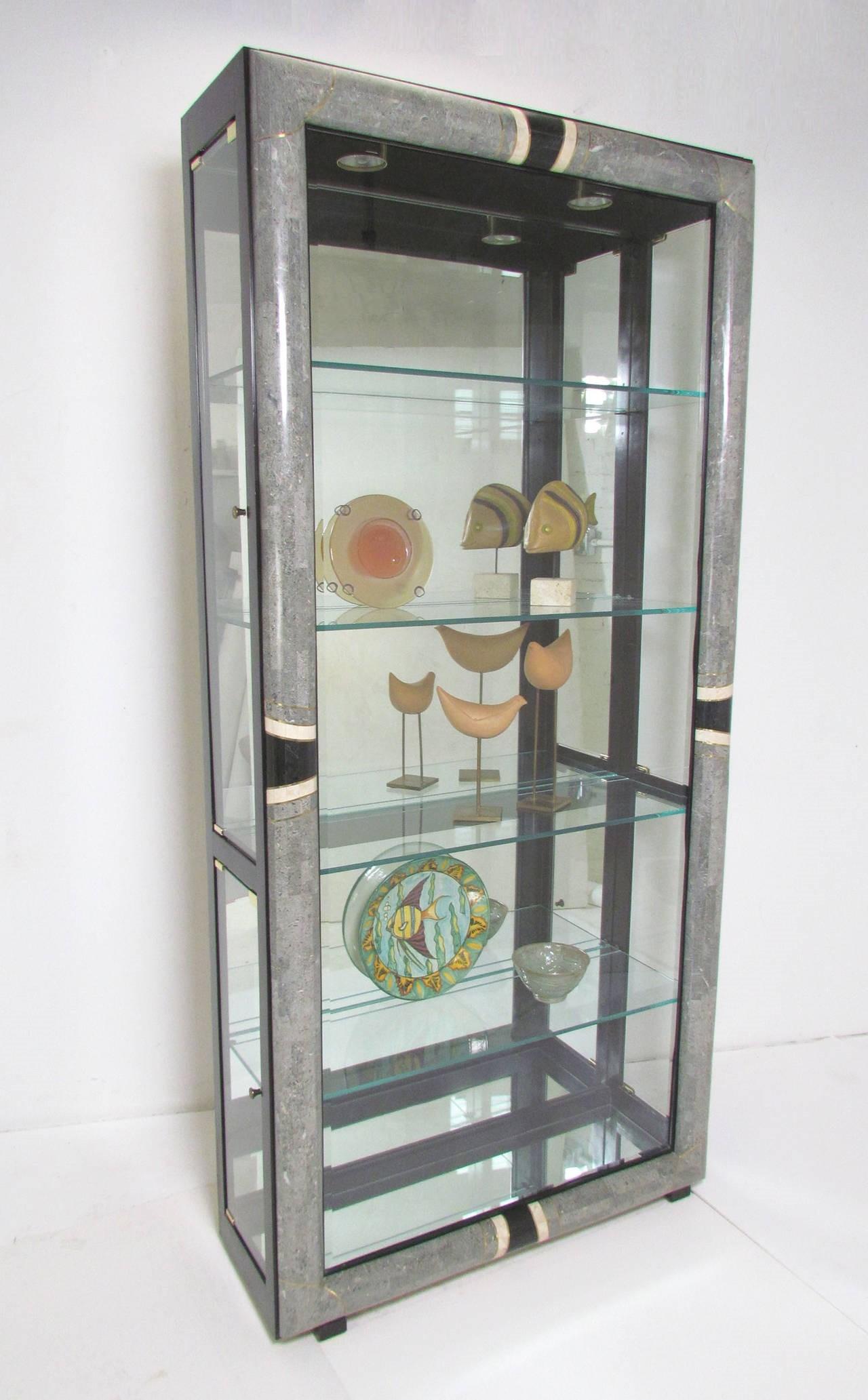 This is a stunningly beautiful pair of vintage tessellated stone Art Deco styled display cabinets. The front outer frame is covered with a curved band of tessellated stone and edged between the patterned portions in brass, mirrored back and case