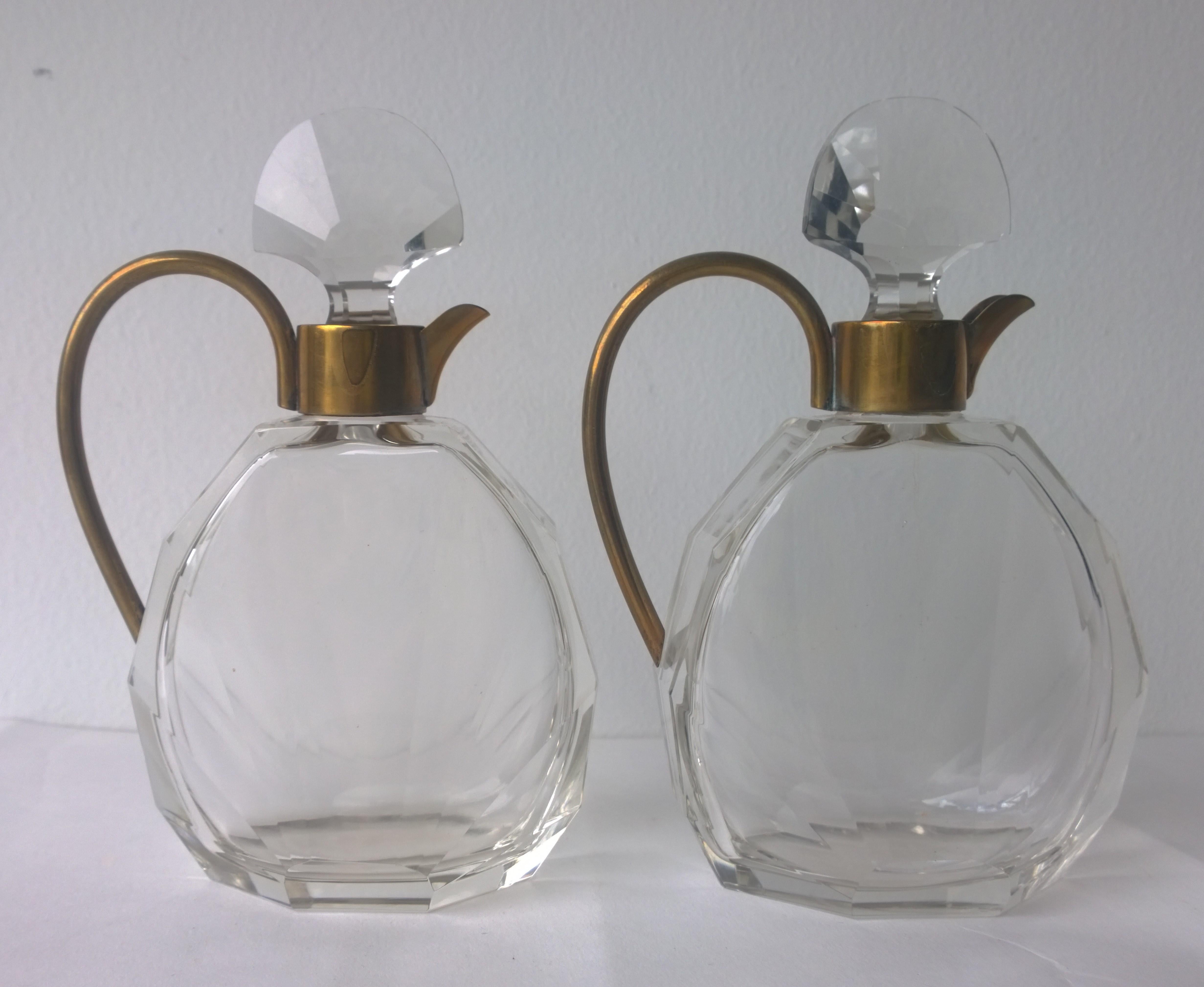Offered is a pair of Art Deco faceted glass and brass decanters. This beautiful Art Deco designed pair is a mirror image of one another. The decanters were probably used for oil and vinegar. This pair of decanters, whatever its use, is a little gem