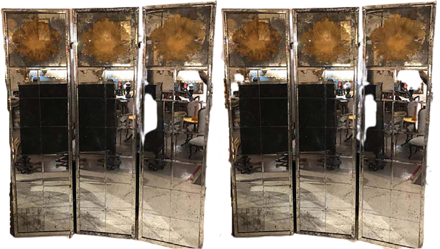 Monumental pair of Art Deco fashioned three-panel mirrored room dividers or folding screens. These simply spectacular shell carved distressed mirror panels are certain to add jaw dropping reflection to any room in the home or office. Purchased from