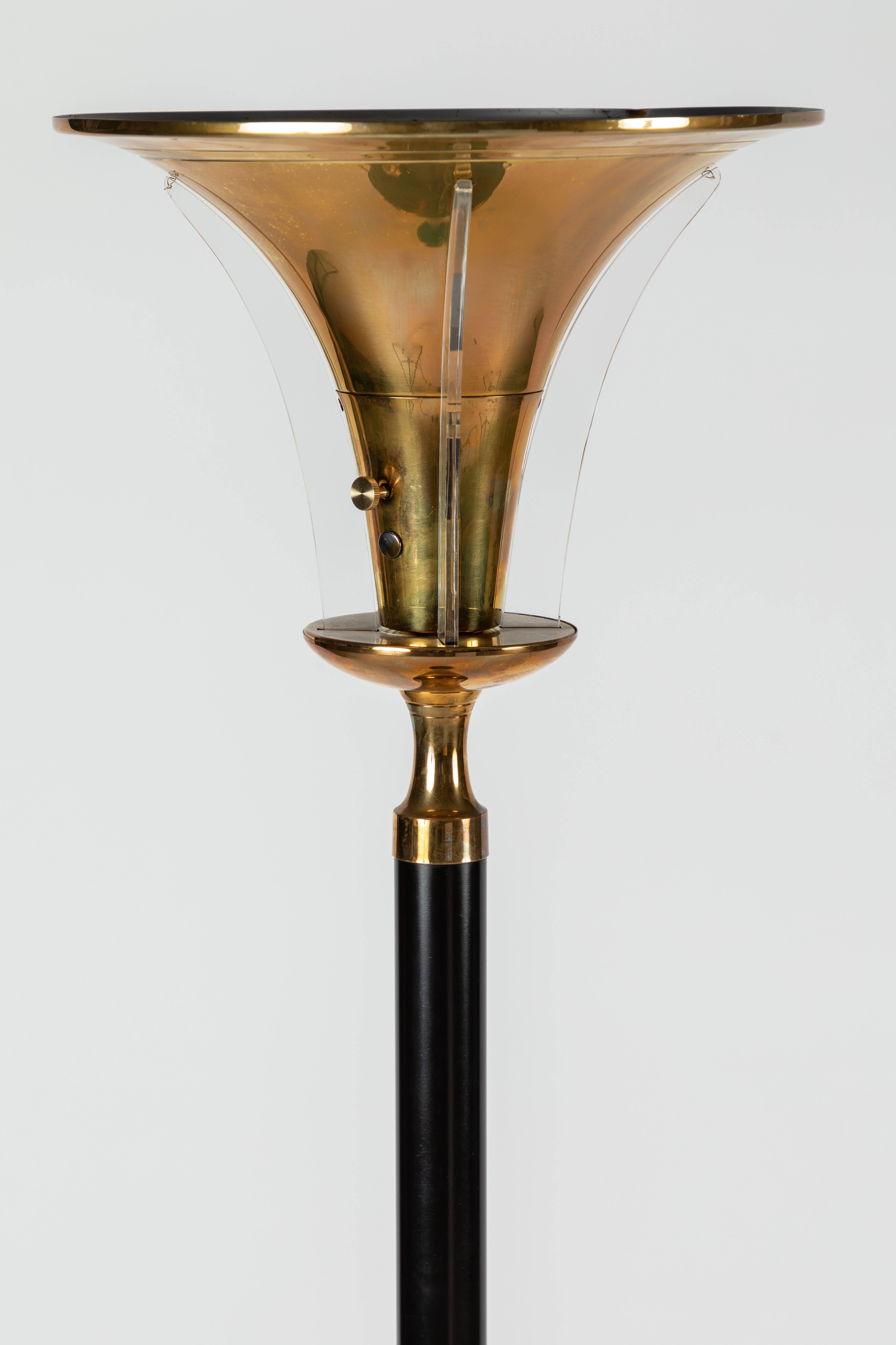 A pair of Art Deco floor lamps with organic, trumpet-shaped brass shades with piercings that allow the addition of Lucite fins to illuminate. 

Materials: spun aluminum with brass components and Lucite. 

Model number C5043 engraved at the