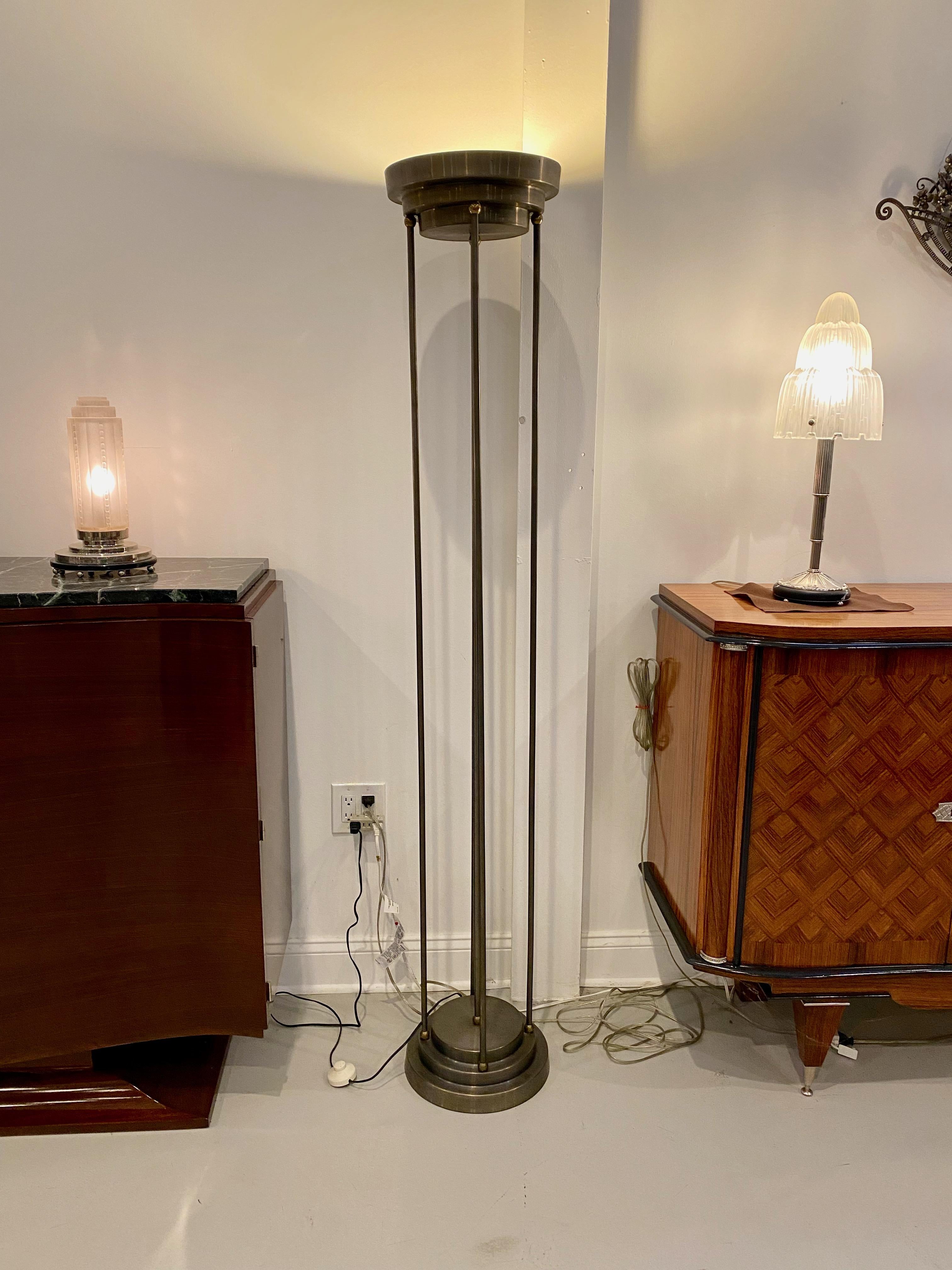 Pair of Art Deco floor lamps with stepped base and matching stepped top. The nickel stepped base has five rods that lead up to the mirror stepped top. Has been rewired for American use with two medium base sockets in each floor lamp.