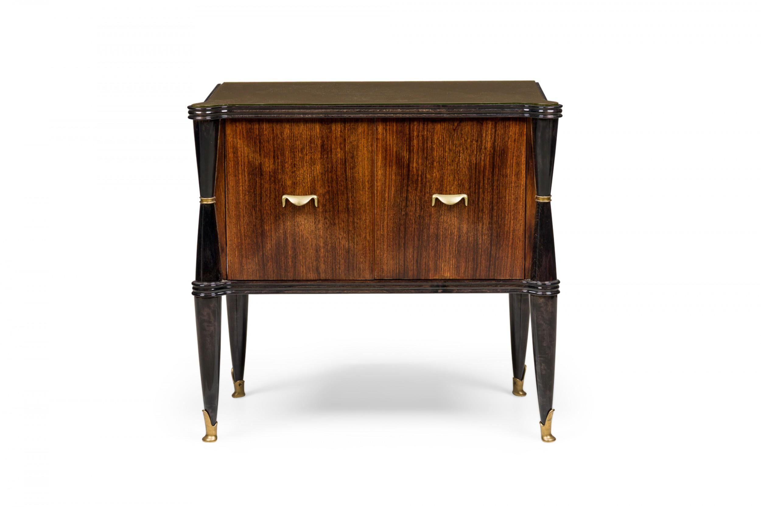Pair of Art Deco French (bedside) commodes in rectangular form with a shaped, molded ebonized trim enclosing an inset glass top, two fitted hinged doors with bronze lip pulls revealing an interior compartment, standing on ebonized turned legs with