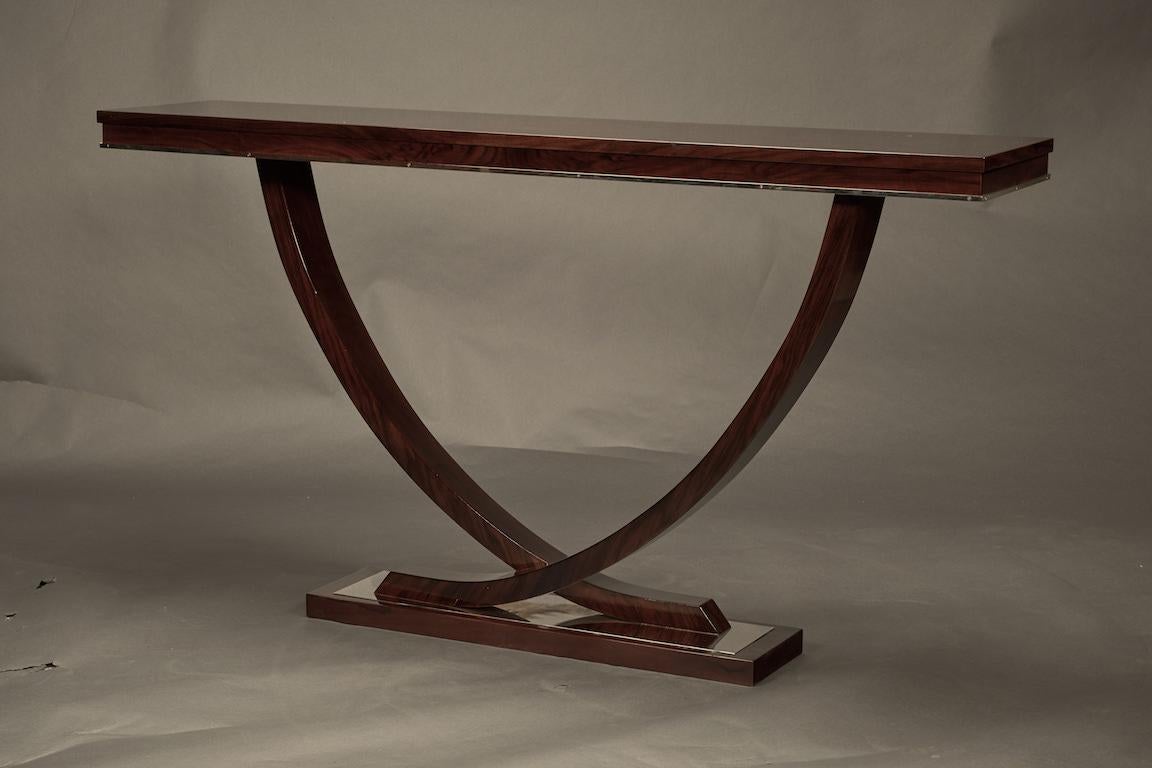 Wide top of the console is made out of high quality walnut wood. Elevating elements are 2 semi-circular wooden legs that are connecting with each other and prominently attached to the rectangular base. Base is decorated with chrome plate.