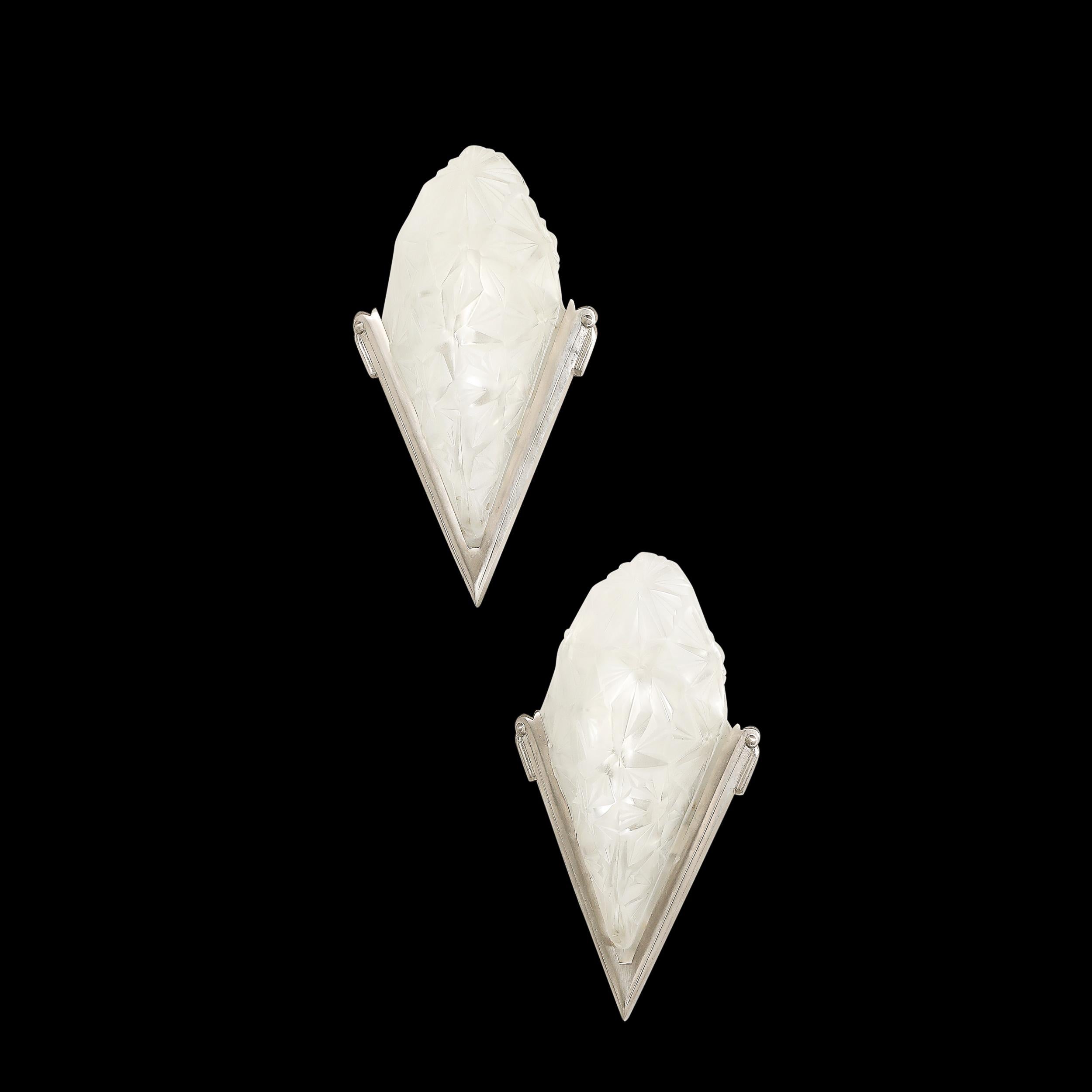 This exceptional pair of Art Deco slip shade sconces, signed by the renowned French glassmaker Degué and crafted in France circa 1935, exemplifies the era’s daring fusion of artistry and modernism. The frosted glass shades are adorned with a