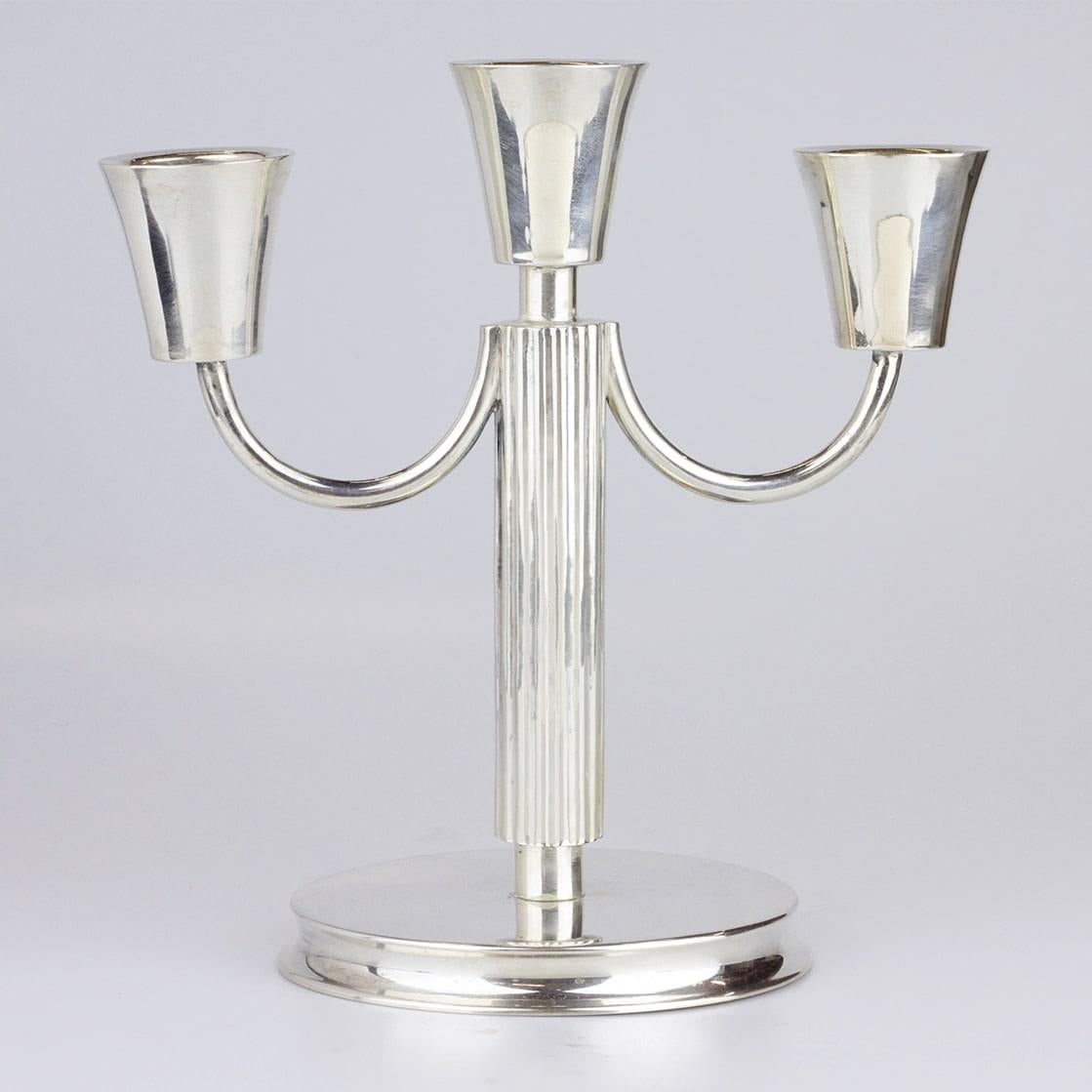 This pair of three light candelabras are made from 800 purity German silver and date to the first half of the 20th Century. The pair sit on round bases and have columnar shafts from which stem two further curved arms. The pair are marked for
