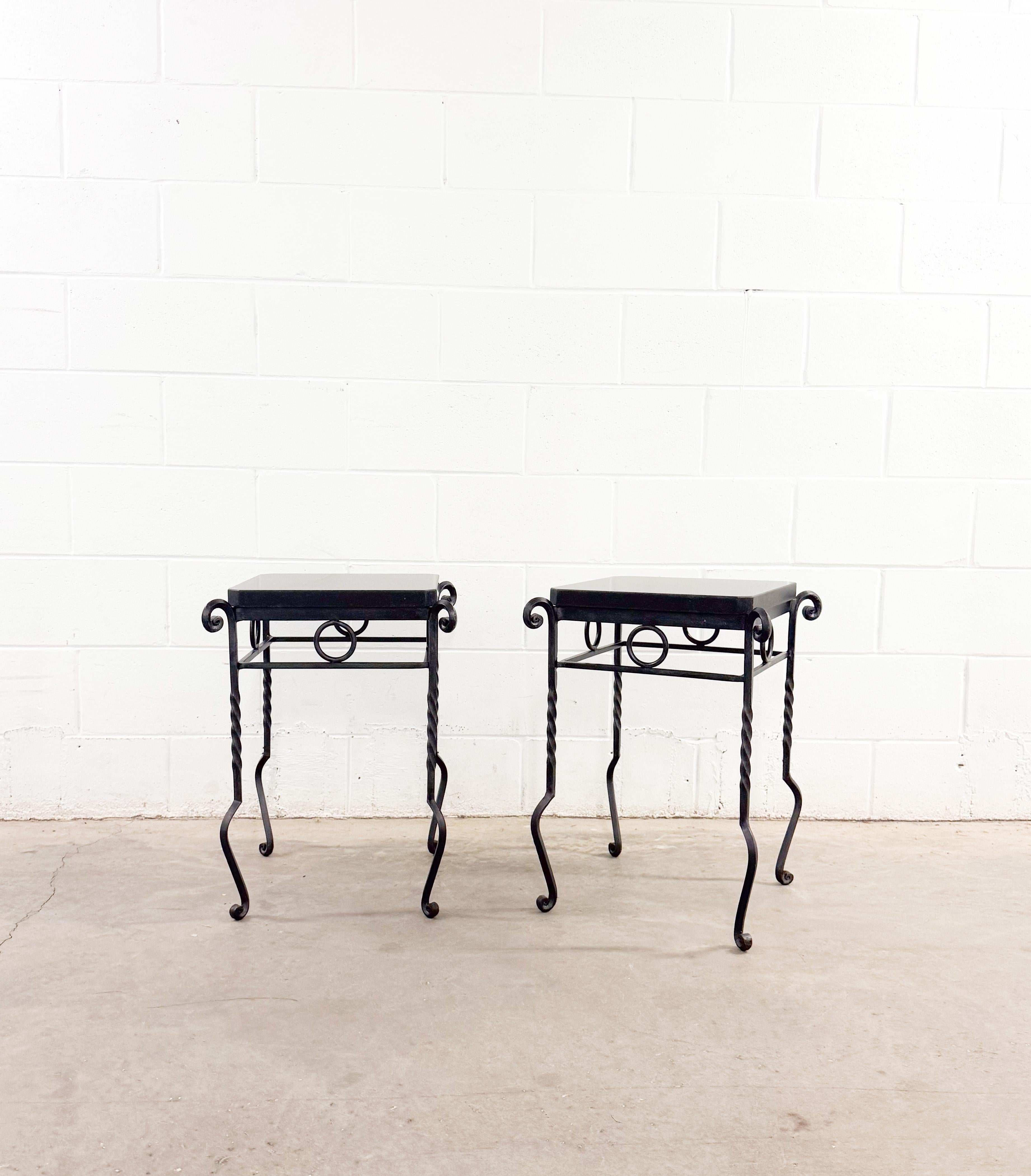 Whimsical pair of Art Deco Giacometti-style side tables crafted from forged wrought iron and granite. Charming yet modern, they feature a lightly polished granite top, twisted-iron legs, and turned feet. The heavy granite tabletops are