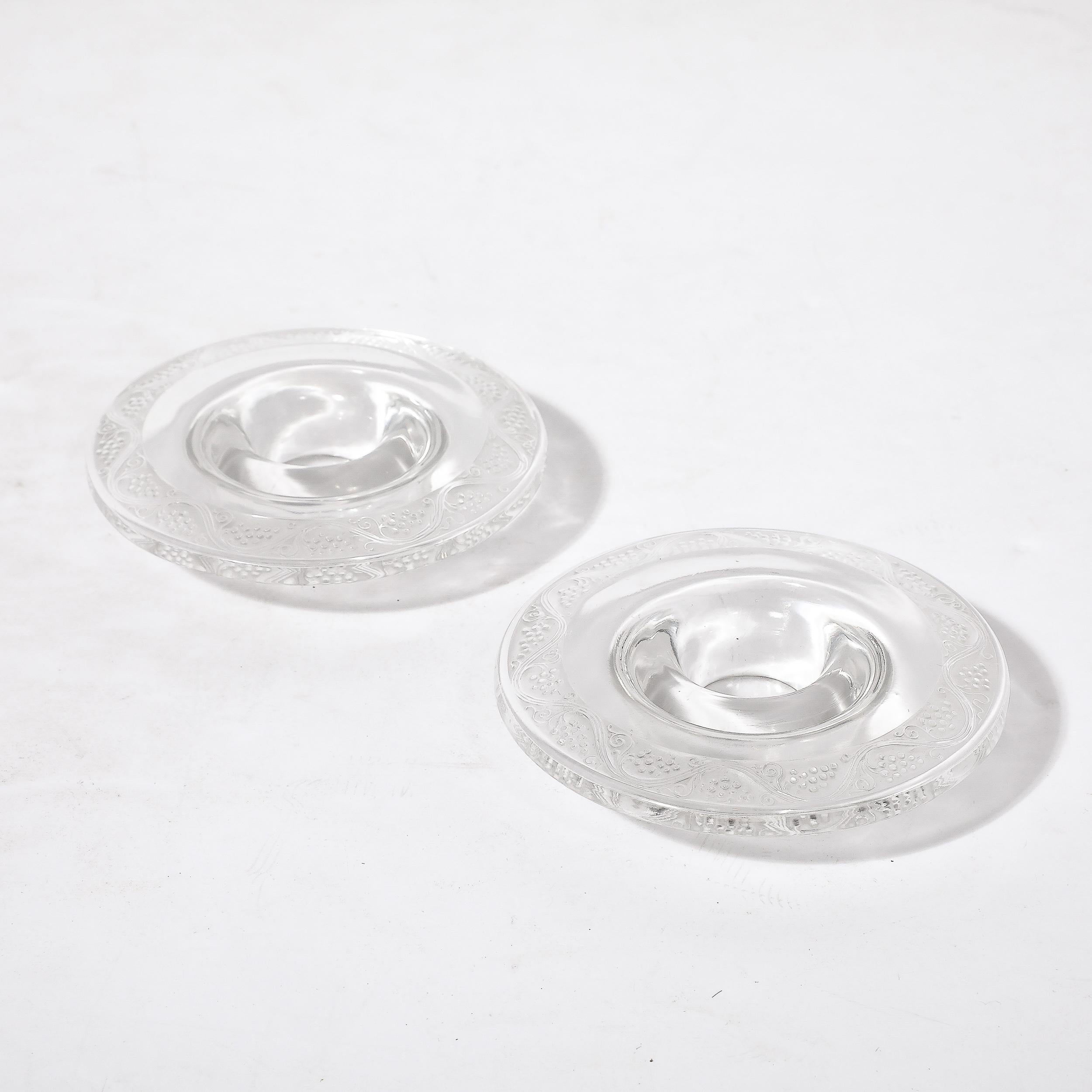 Cette magnifique paire de verres Art Déco  Bougeoirs avec motif de vigne signé R. Lalique originaire de France, Circa 1930. D'une échelle réservée et très utilisable, ces bougeoirs sont réalisés en cristal transparent avec des motifs de vigne moulés