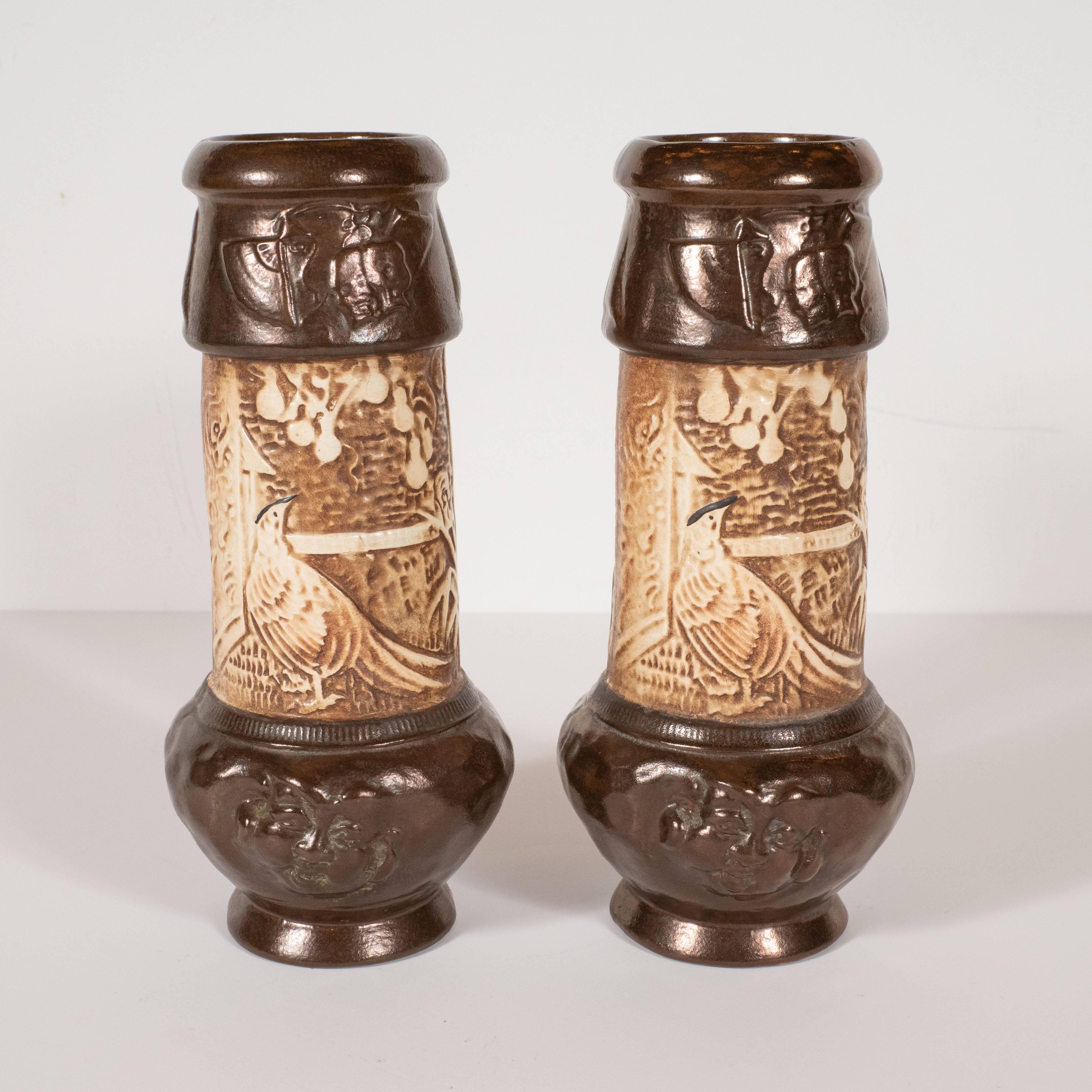 This sophisticated pair of hand-painted ceramic vases were realized by the esteemed British early 20th century pottery studio, Bretby. Hand-painted in dark chocolate and cream tones, they feature whimsical interpretations of orientalist motifs-