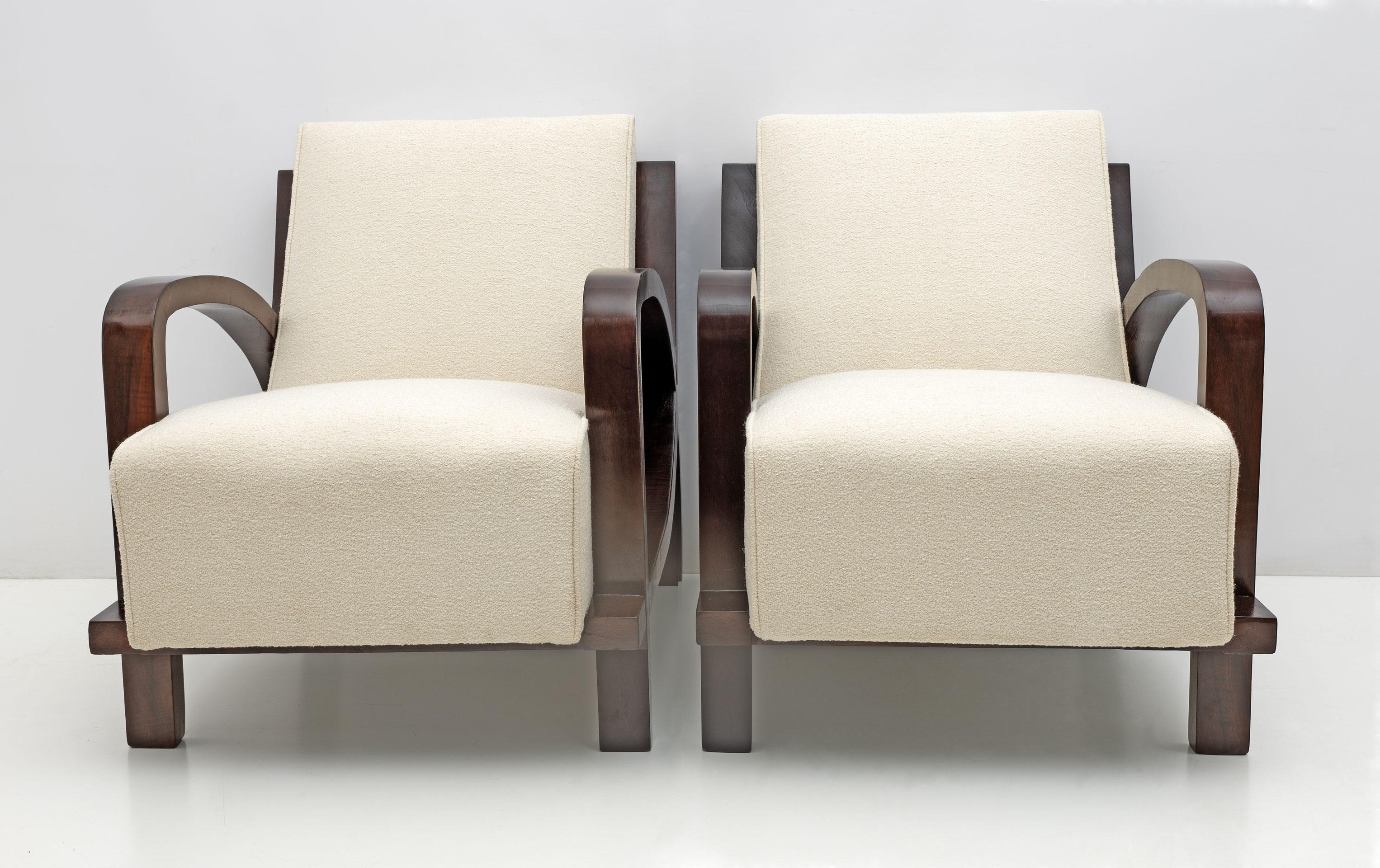 Extraordinary armchairs restored and upholstered in fine ivory-coloured Bouclè. These armchairs have a very dynamic and abundant appearance, beautifully curved and walnut veneered armrests and backrest, which match naturally with the upholstery. The