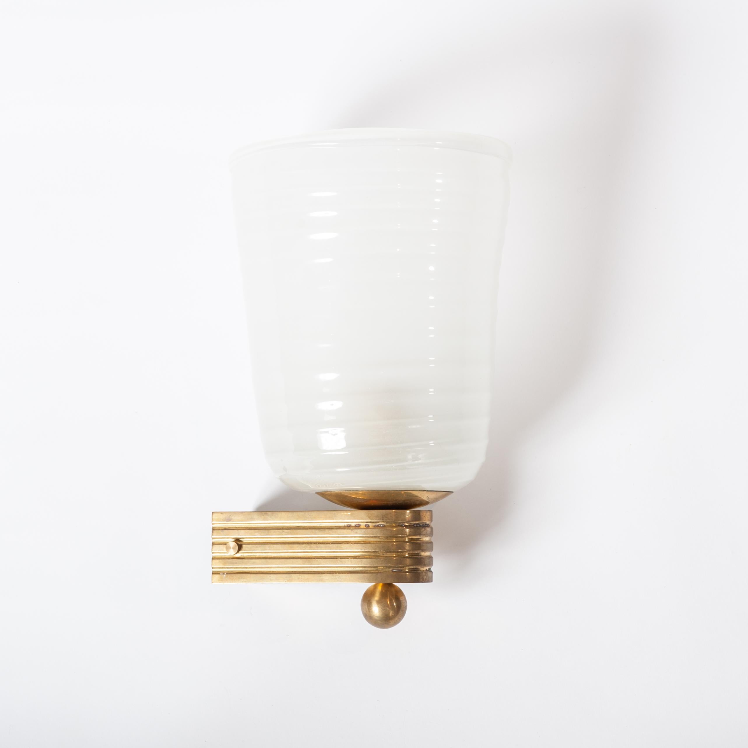 These sconces consist of 2 parts the conic shaped frosted Murano glass shade and the brass mount.
Both parts show a ribbed structure.
The glass has no defects, the brass has a wonderful patina.
(Diameter glass shade above 21cm x below 13cm x height