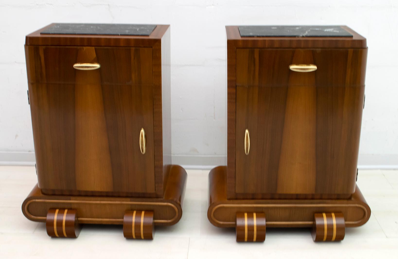 This pair of bedside tables were produced in the 1920s, the Art Deco period. They are covered in Canaletto walnut, mahogany and maple inlays, the structure is in poplar, the handles are in bakelite and the top in black Marquina marble. They have