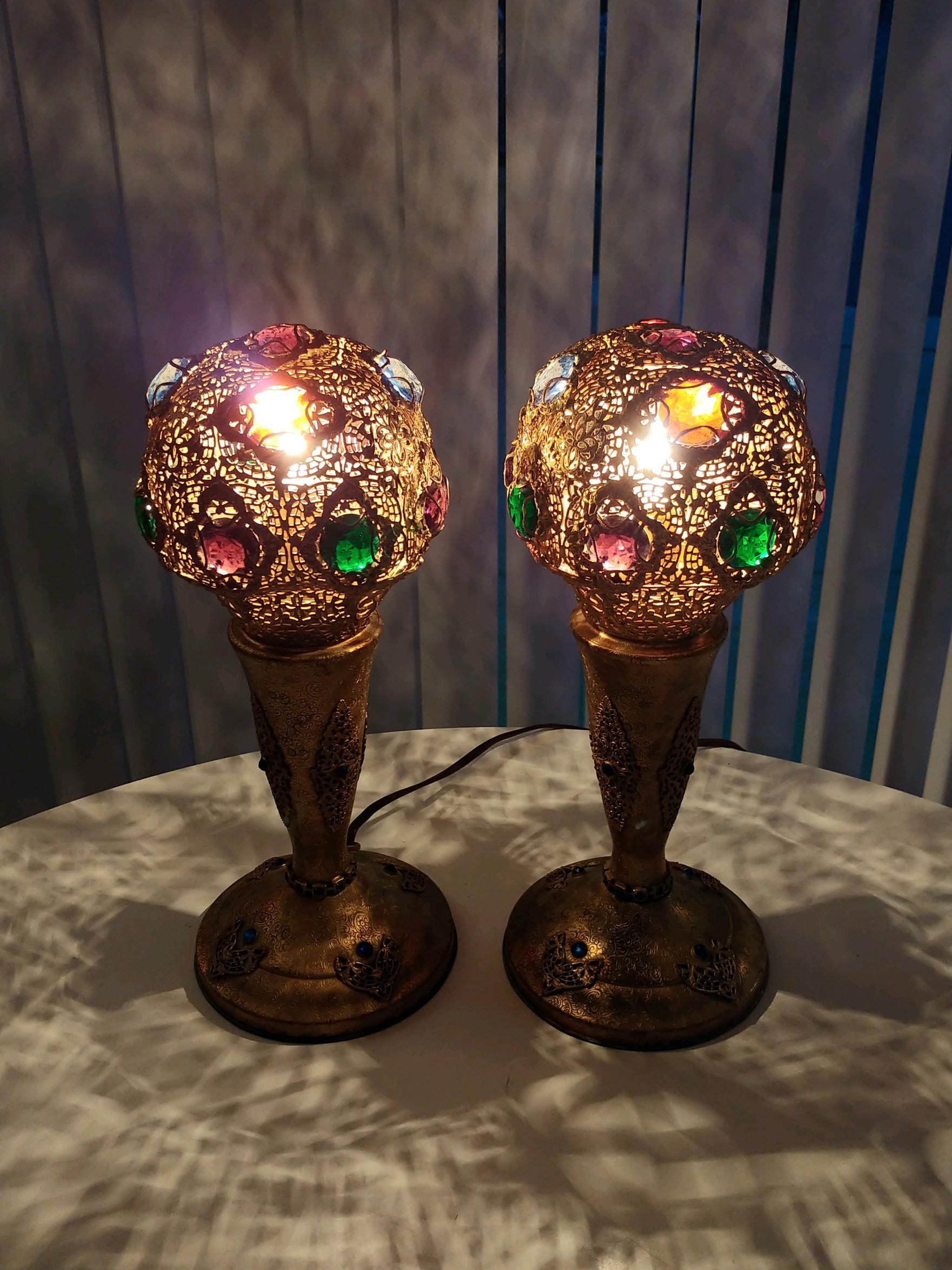 A matched pair of circa 1920's jeweled and filigreed accent lamps by Apollo Studios of New York. These are unsigned but are unmistakably Apollo Studios. Purple, amber, blue and green jewels are set into the removable shades and the bases are adorned