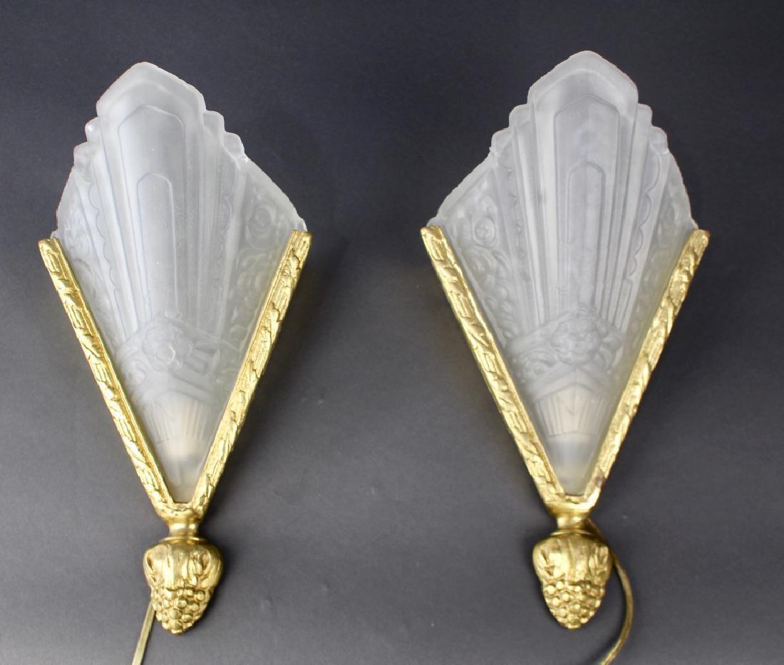 Pair of Lalique style frosted glass single light wall sconces in the Art Deco style. The pair set in brass frames each terminating in a pineapple.
1EX.