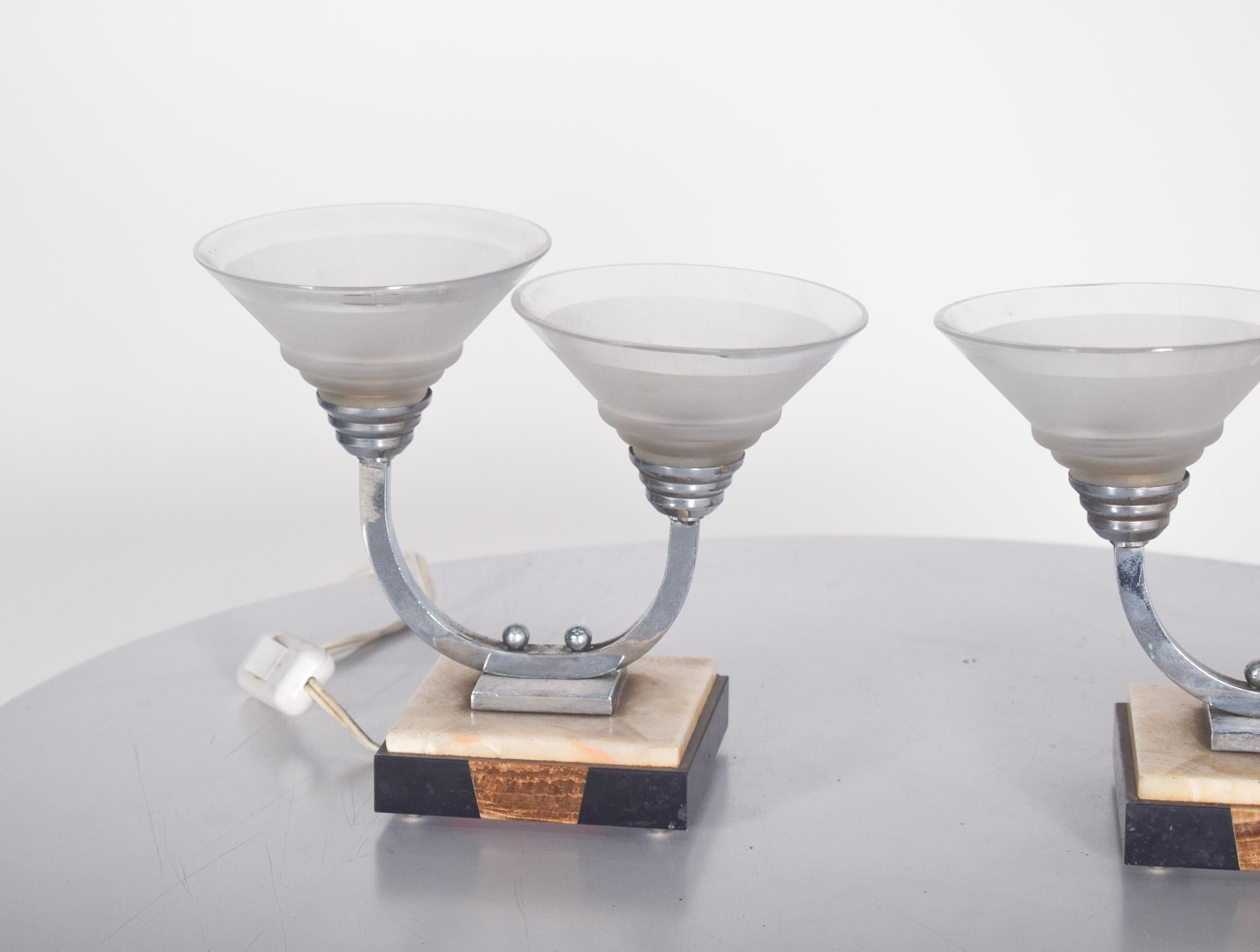 Paire d'abat-jour Art Déco. Base en marbre bicolore soutenue par quatre pieds, avec deux abat-jour en verre en forme de coupe de différentes hauteurs soutenus par une structure en forme de U. Composé d'une base rectangulaire en marbre, avec des