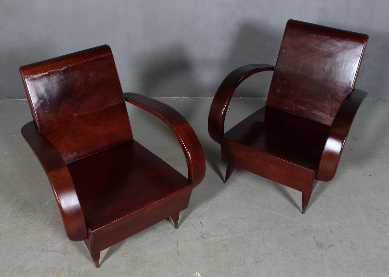 Pair of art deco lounge chairs made in partly solid exotic hard wood.

Curvy armrests.

Legs with brass details.

Made in the second half of the 20th century.

Minor height differences. Can be accompanied by a cushion for extra support in