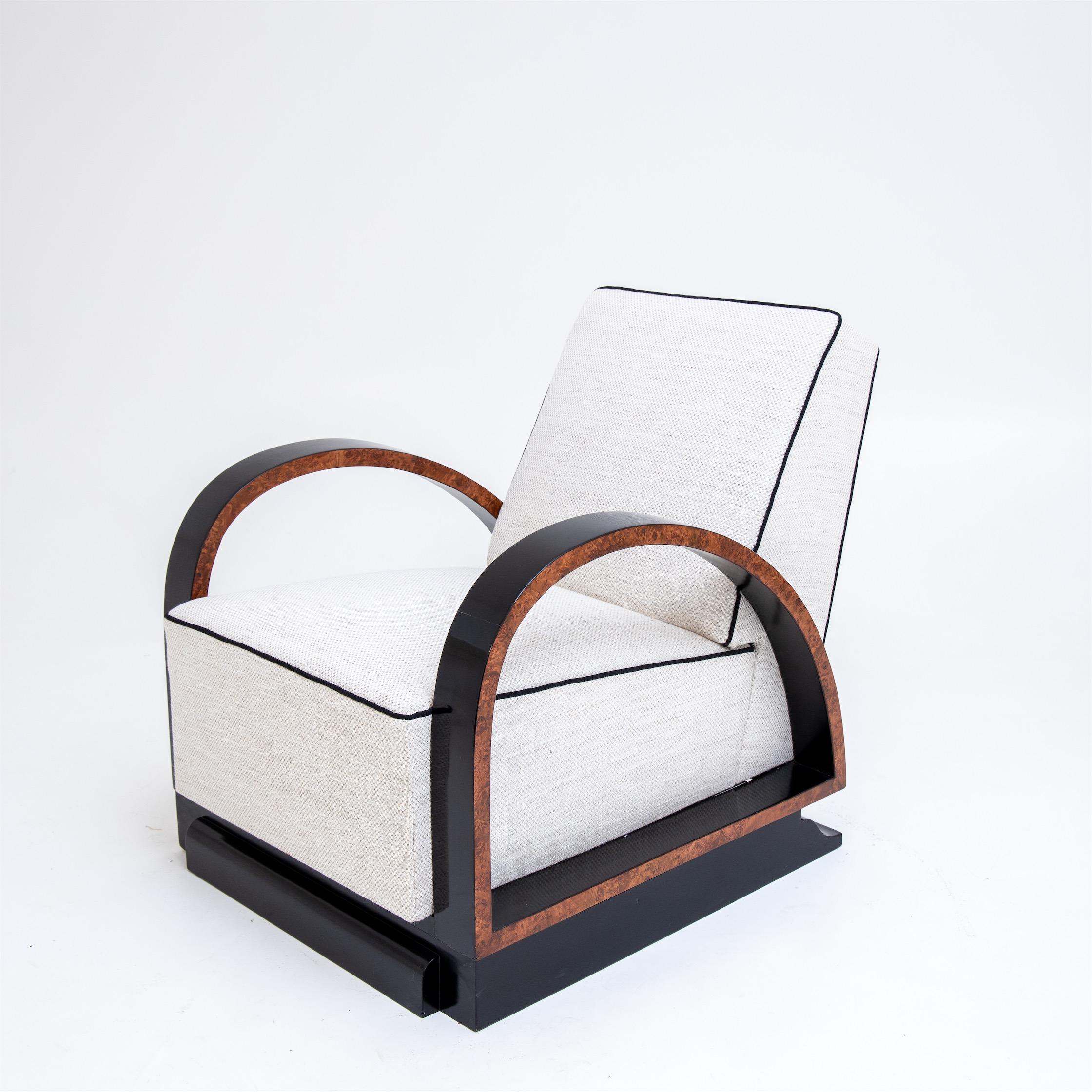 Fauteuil sur une structure en bois massif avec des accoudoirs arqués. 
Le fauteuil a été nouvellement tapissé d'un tissu blanc avec un passepoil noir et poli à la main.
 