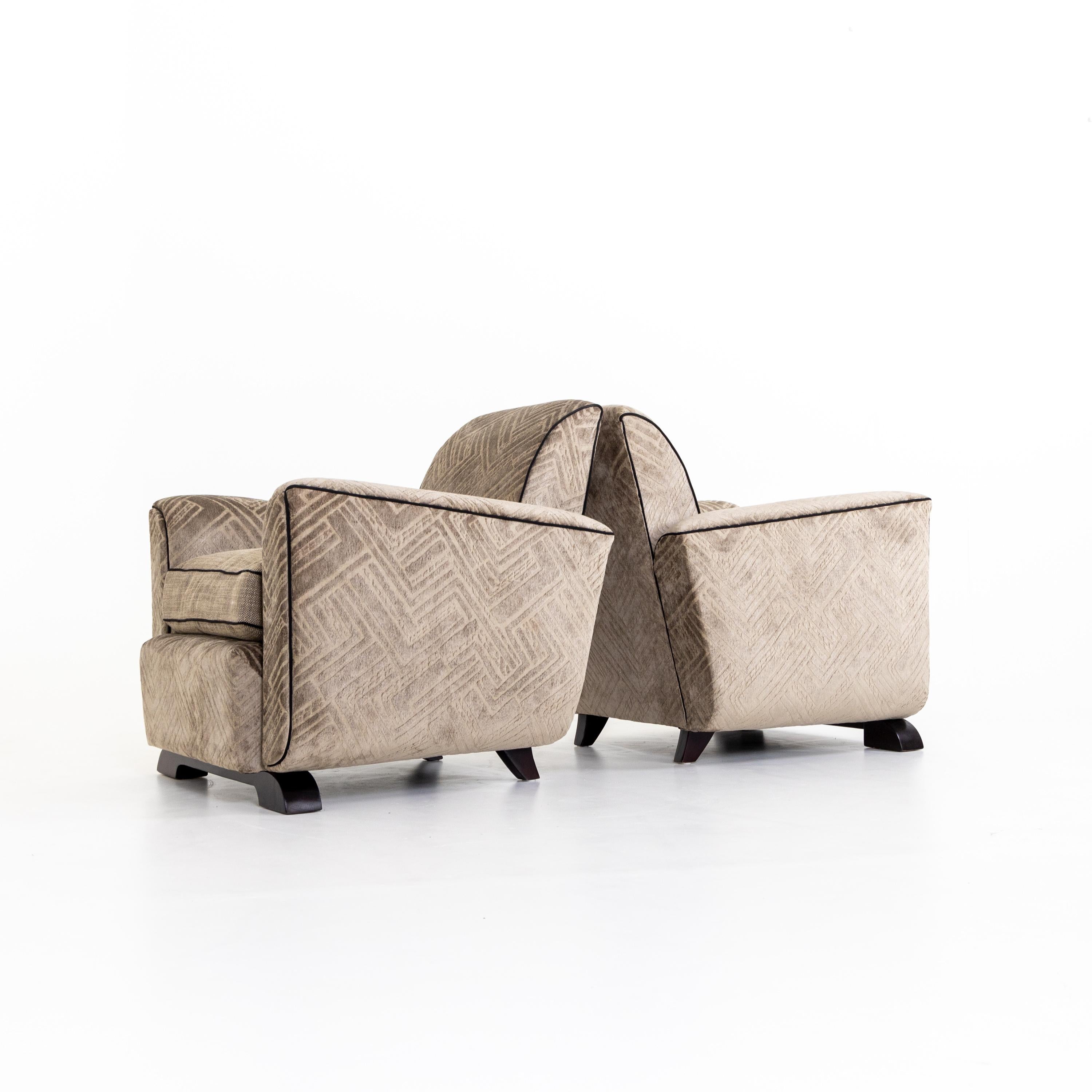 Pair of Art Deco armchairs with upholstered, slightly tulip-shaped seats standing on wooden legs. The armchairs have been reupholstered in a gray-brown fabric with a geometric pattern.
