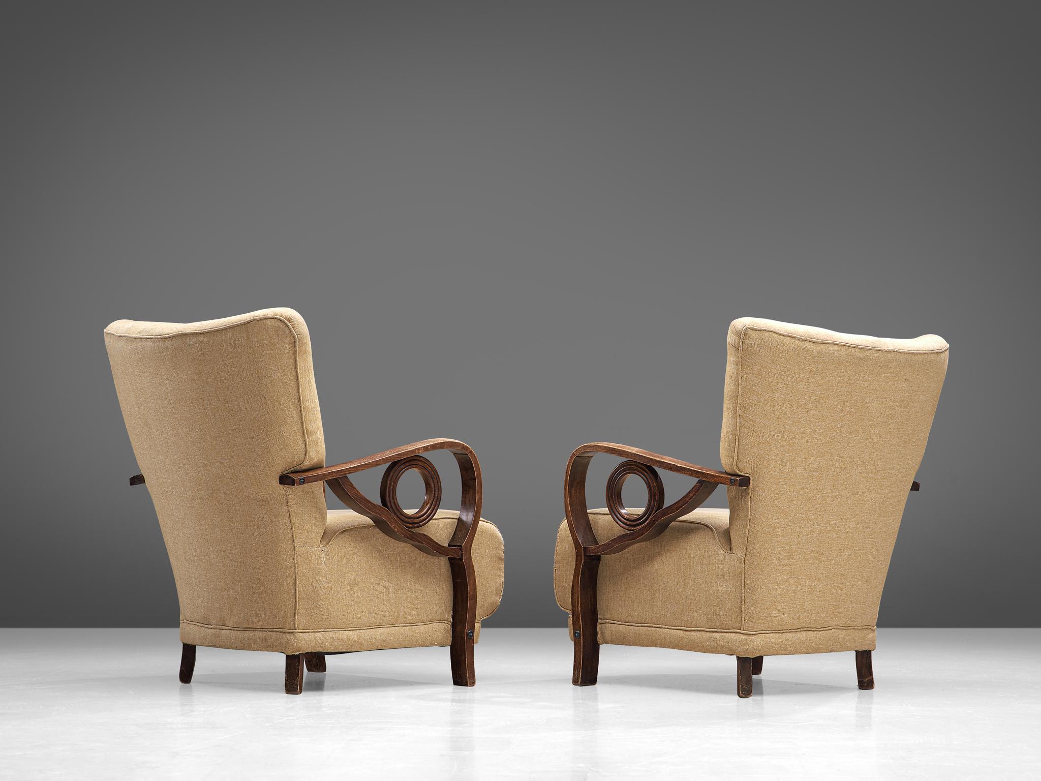 Pair of armchairs, oak and fabric, France, 1940s

The most distinctive feature of these Art Deco lounge chairs are the stained oak armrests that are curved with elegant details, such as the circular element in each arm. The seat is wide and the