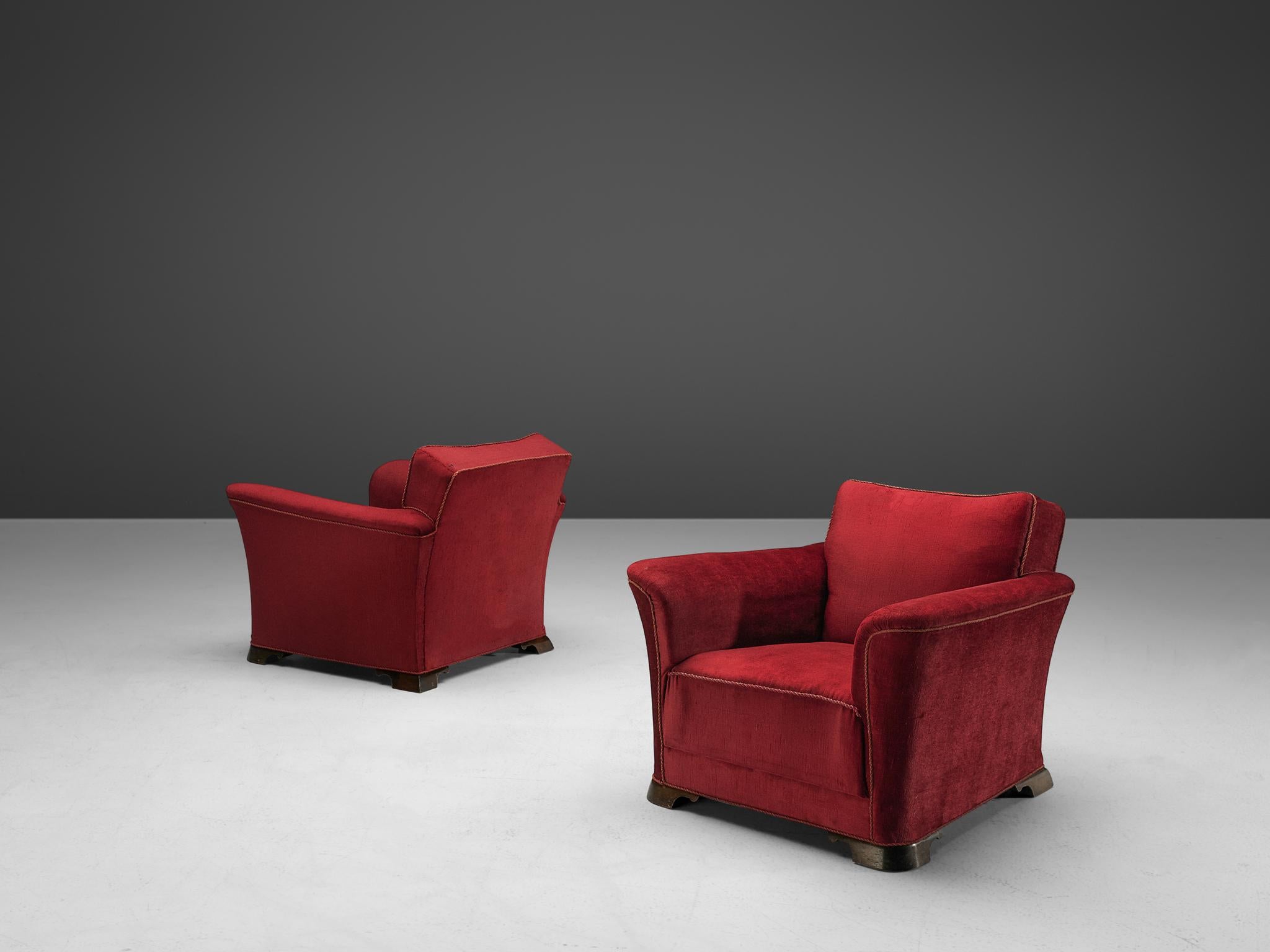 Pair of lounge chairs, velours, oak, Denmark, 1940s

A pair of two grand and comfortable armchairs in red velours upholstery. The lounge chair features a thick seat, which is characteristic for the Art Deco movement. Large upsweeping armrests curve