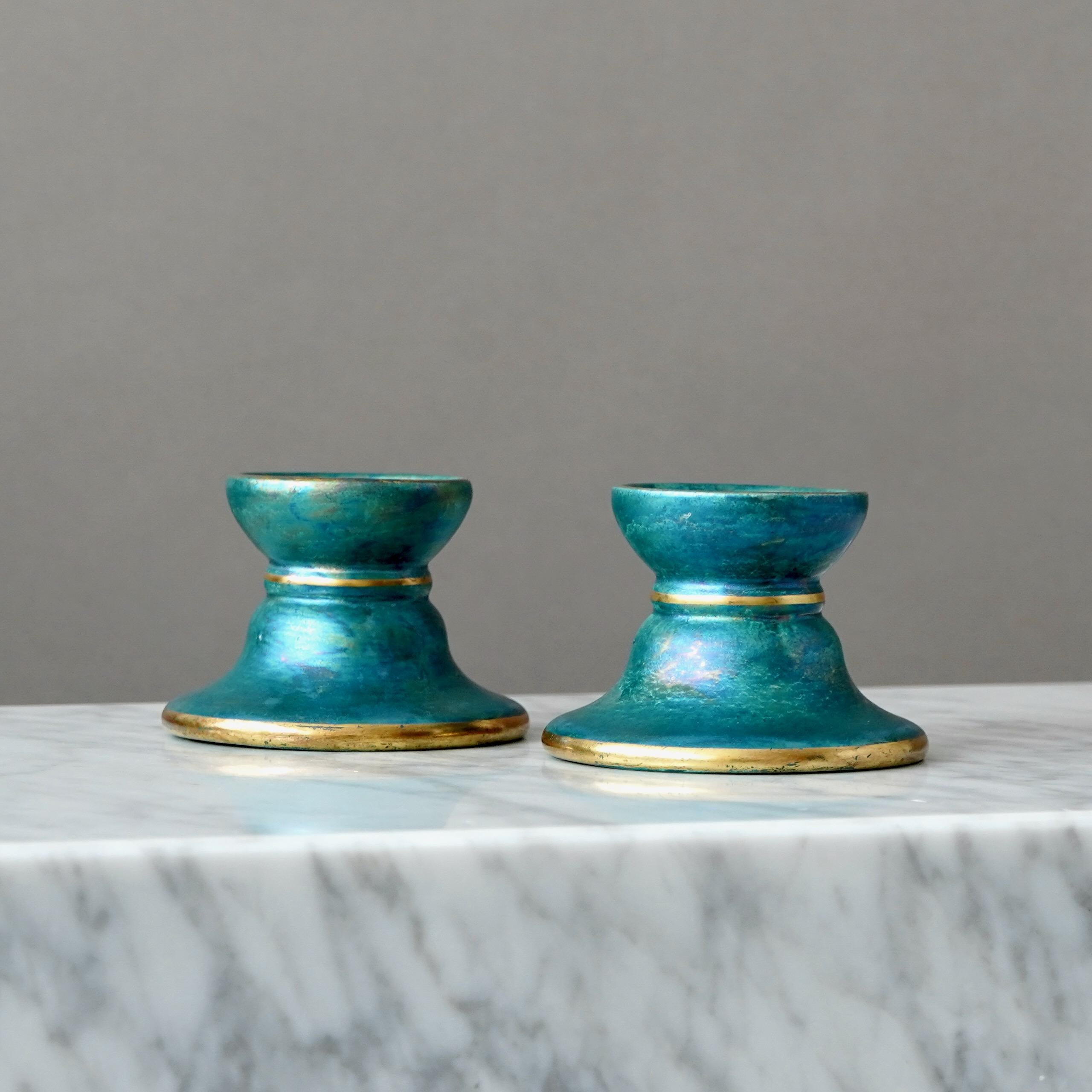 Una coppia di candelieri con un'incredibile smaltatura a lustro e dettagli dorati dipinti a mano. Grazia scandinava / Art Deco.
Realizzata da Josef Ekberg a Gustavsberg, Svezia, negli anni '1930.

In buone condizioni, ma con qualche segno di usura