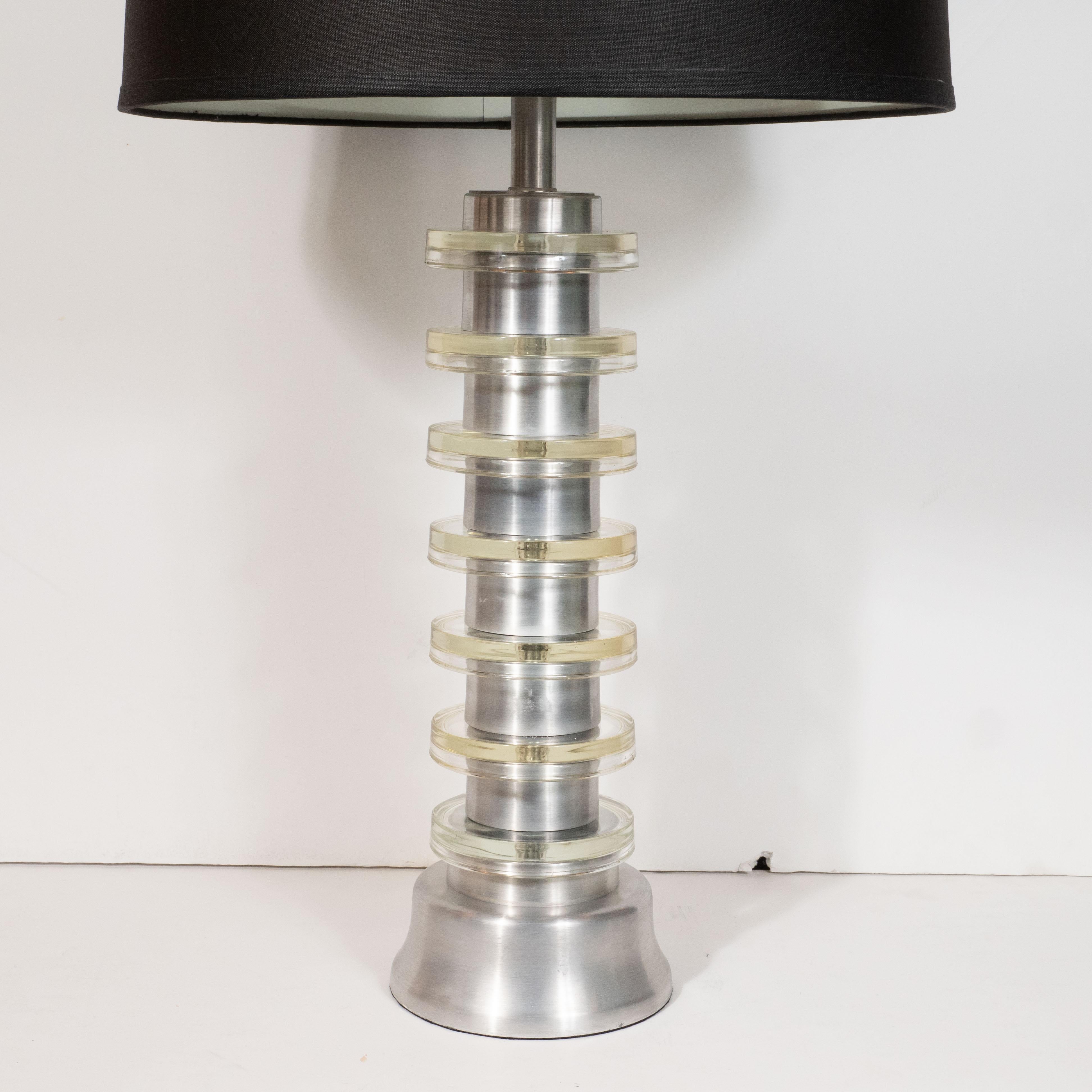 This sophisticated and sculptural pair of Art Deco Skyscraper style Machine Age table lamps were designed by the legendary Russell Wright in America, circa 1940. They feature brushed cylindrical aluminum bodies ringed with seven tiers of circular
