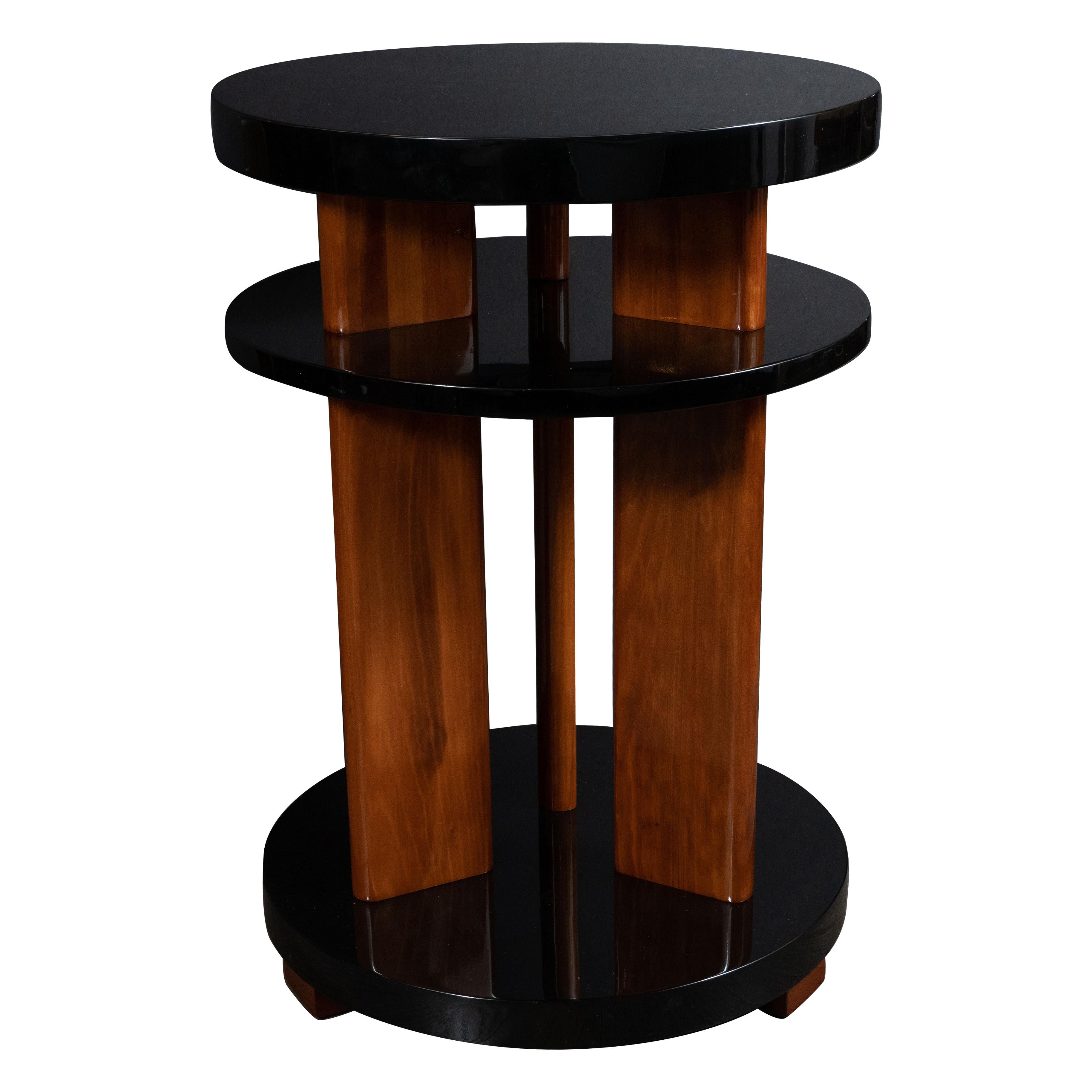 This stunning pair of Art Deco Machine Age side or occasional tables were realized in the United States, circa 1935. They feature three circular tiers in black lacquer resting on rectangular walnut feet. The table is supported by three streamlined