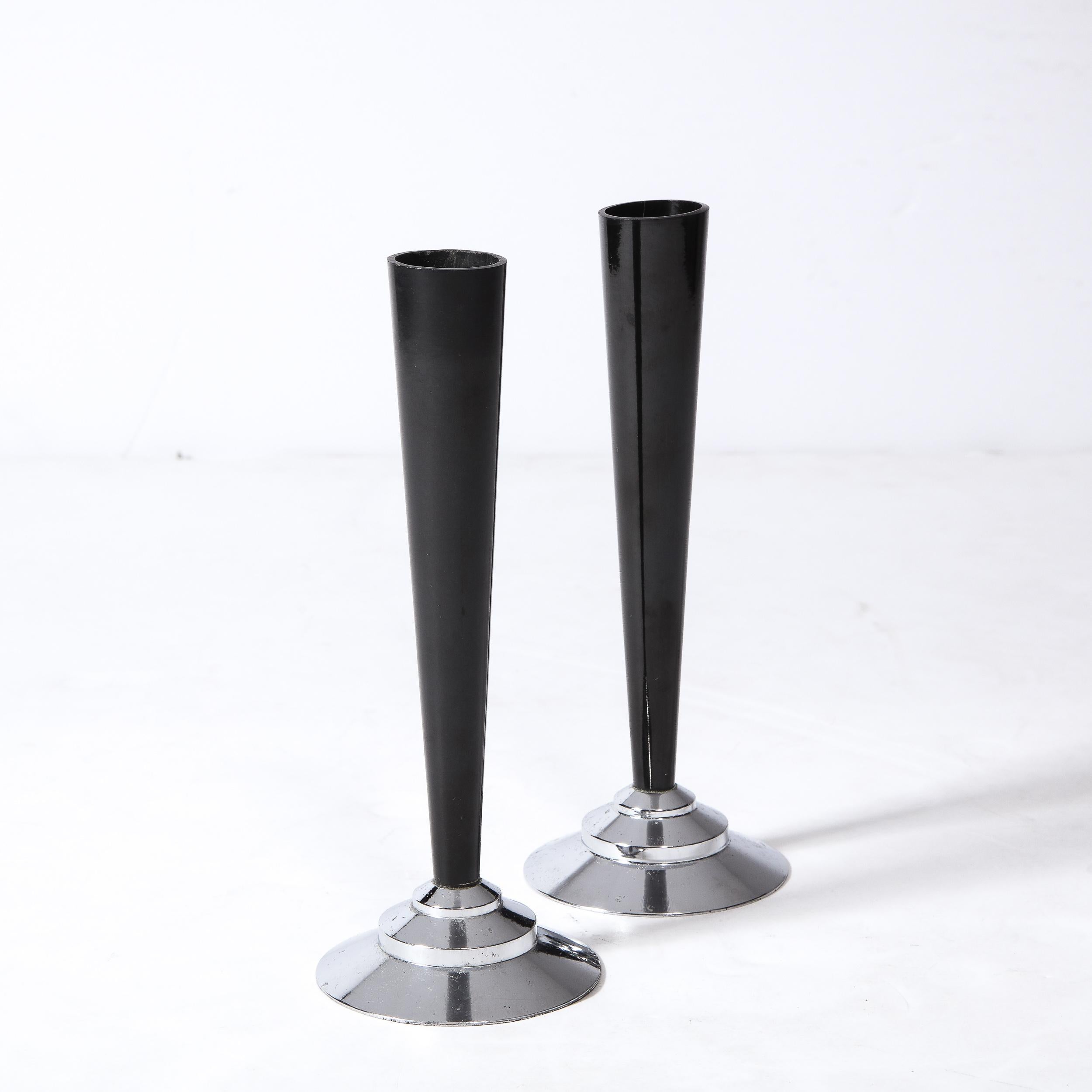 This stunning pair of Art Deco Machine Age skyscraper style vases were realized in the United States circa 1935. They feature tiered skyscraper form bases and tapered cylindrical bodies in black bakelite. With its clean modernist lines and