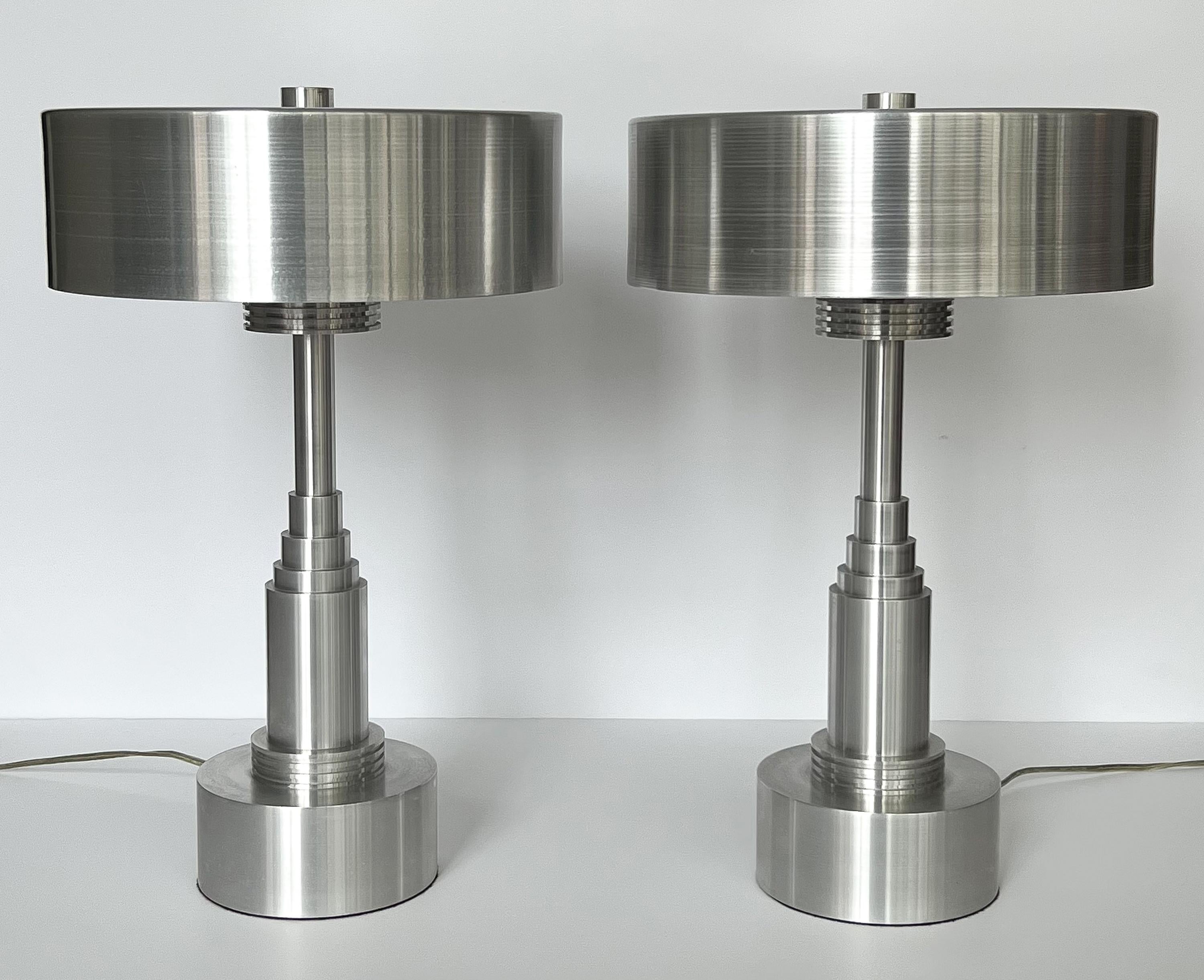 Striking pair of Modernist Machine Age spun aluminum table lamps in the style of Walter Von Nessen, USA circa 1970s.  These lamps feature an Art Deco / Skyscraper stepped design in heavy solid aluminum.  Spun aluminum shades measure 4