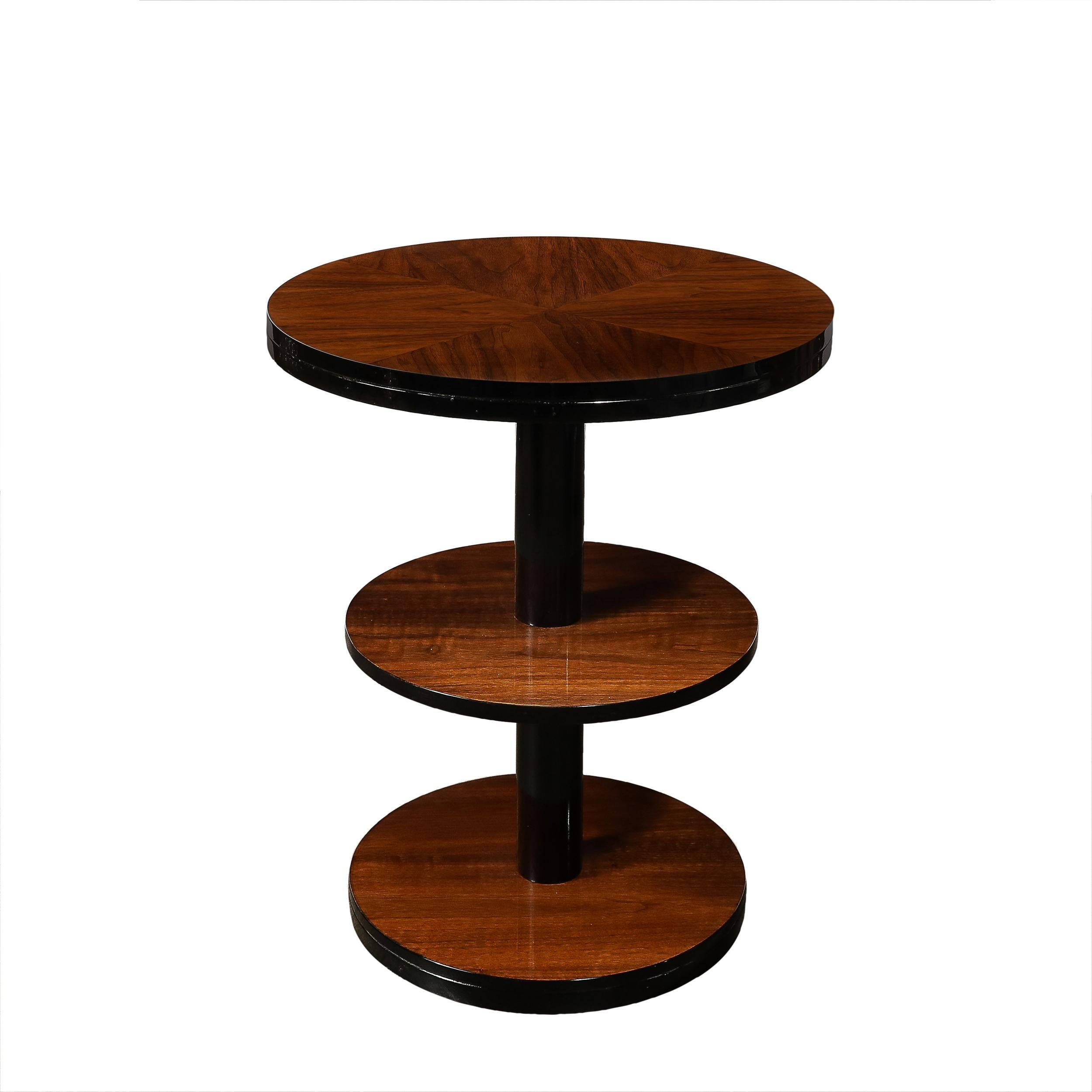 This versatile and materially exquisite Pair of Art Deco Machine Age Three-Tier Round Side Tables in Book-Matched Walnut & Black Lacquer originates from the United States, Circa 1935. Well scaled and with beautiful proportions, these tables serve as