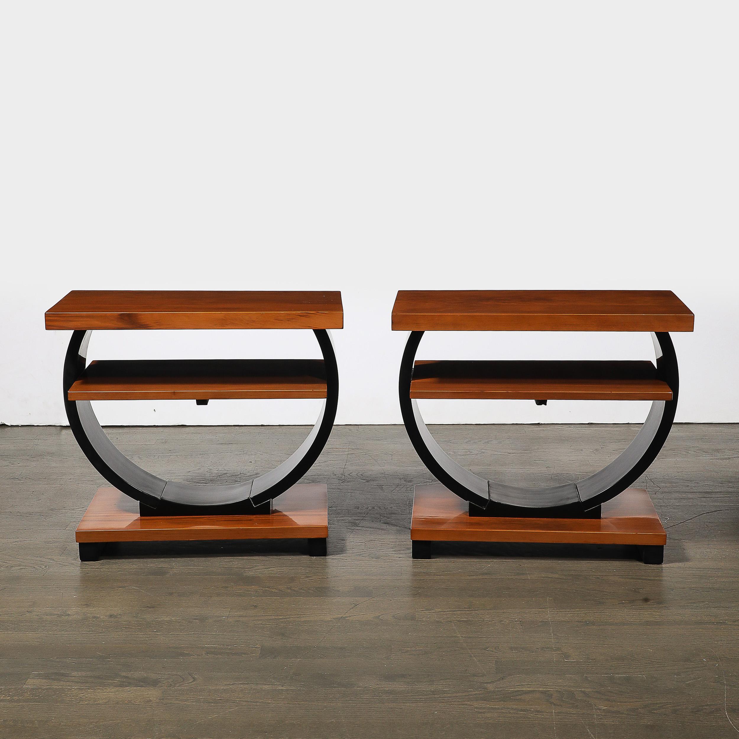 This exquisite pair of Art Deco Machine Age two-tier side tables captures the streamlined elegance and geometric sophistication characteristic of the 1930s. Combining rich walnut and sleek black lacquer finishes, the design highlights the interplay