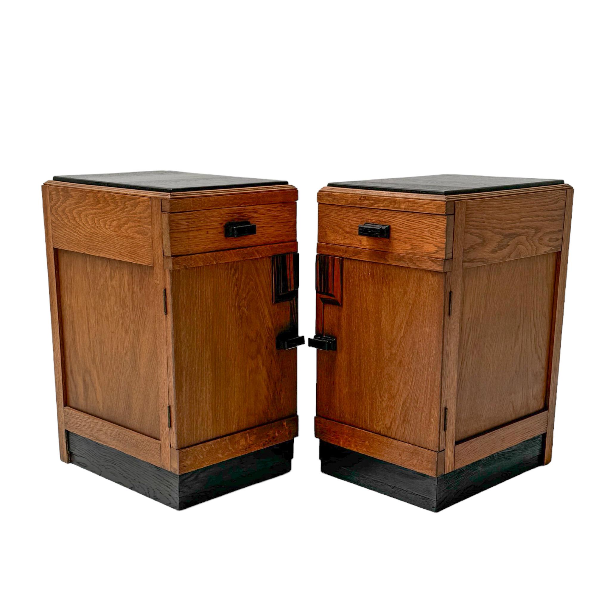 Stunning and elegant pair of Art Deco Modernist nightstands or bedside tables.
Striking Dutch design from the 1920s.
Solid oak and original oak veneered bases with decorative handles on doors and drawers.
Original black lacquered wooden tops.
This