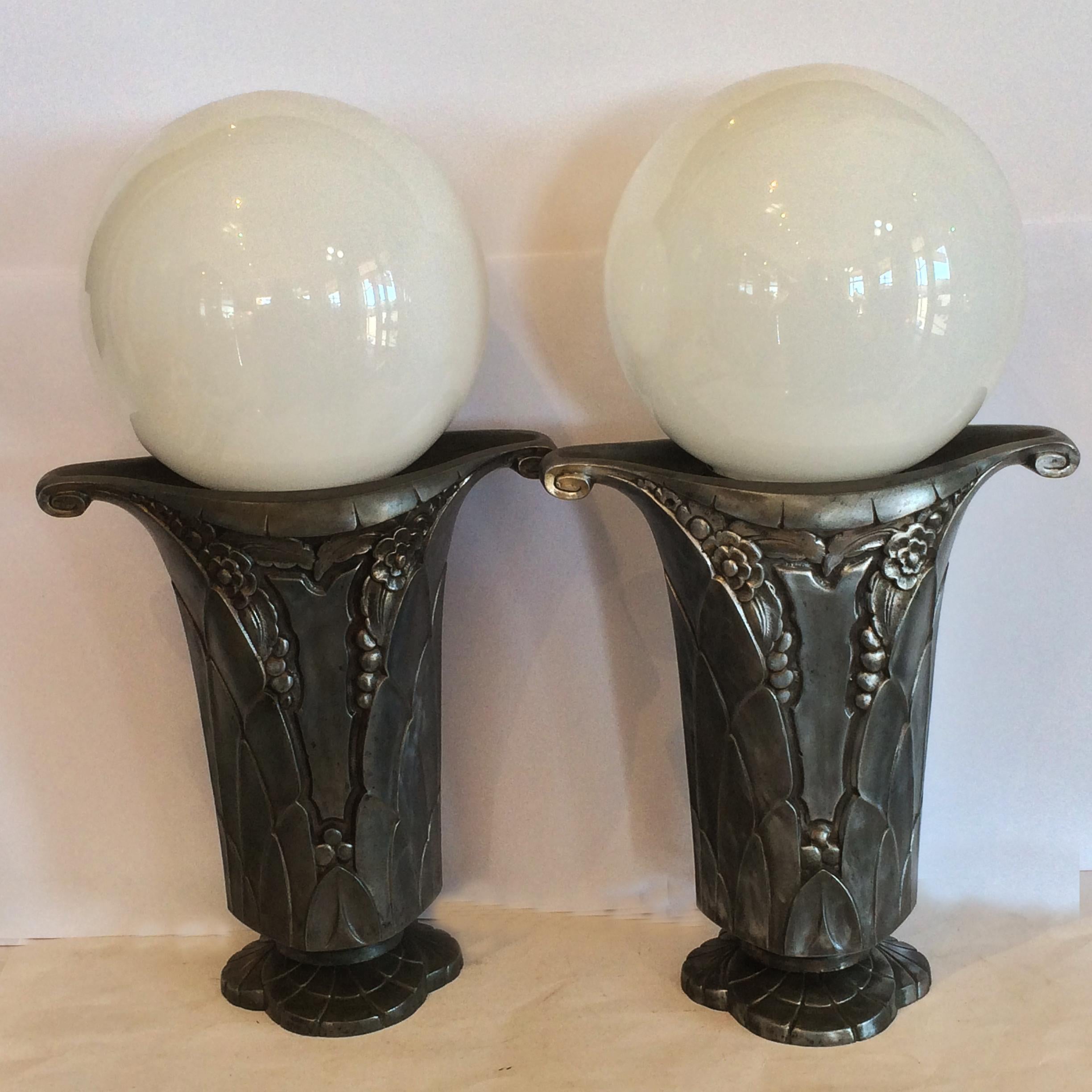 Art Deco pair of French nickel vase lamps with white spheres of light, France. circa 1930. French “Fruit, Flowers, Leaves” influence, to the deep surface design, with undercut throats at base of lamps, cord entering at rear above base, and very fine