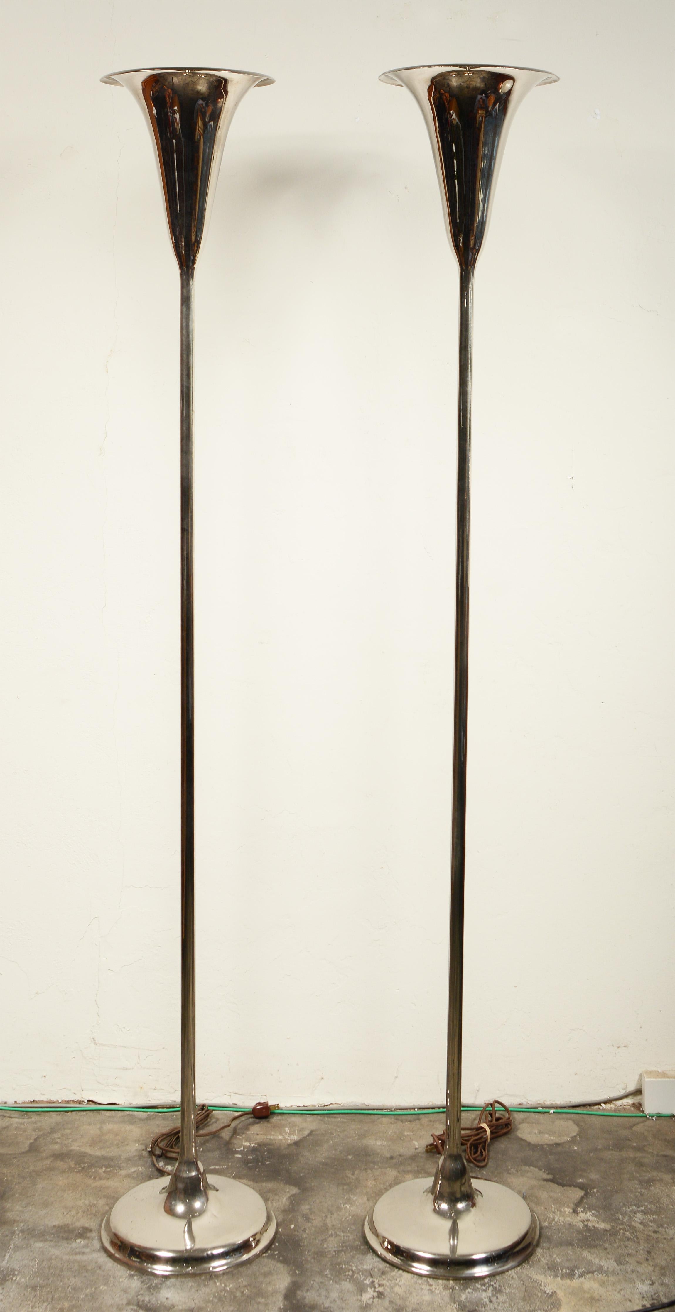 Pair of slender Moderne Art Deco torchieres. These are polished nickel plate. The shade, base and center pole are brazed together so the lamp is one piece top to bottom. There are some small dings to the bases. One base has a small oxidized spot.