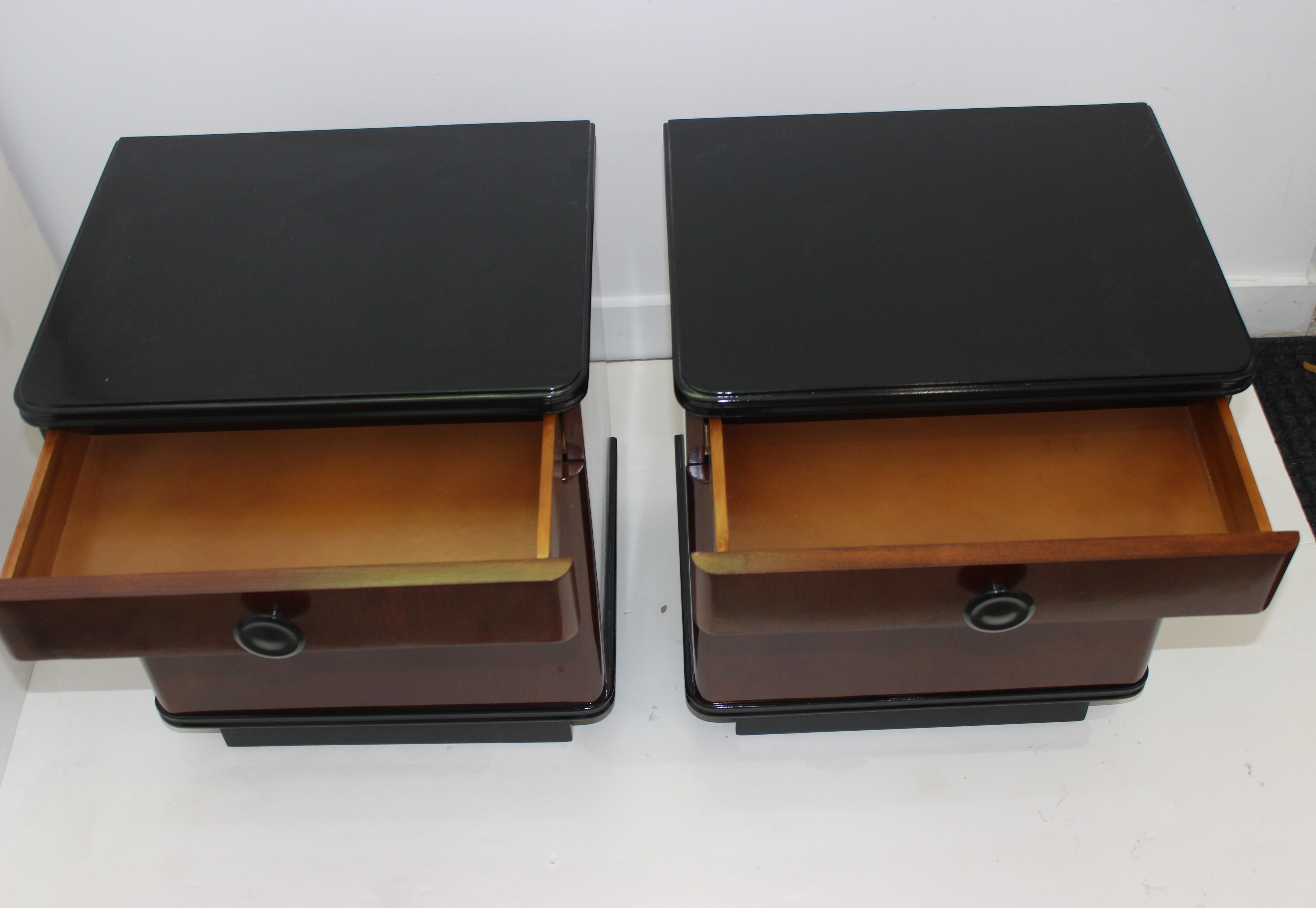 Art Deco nightstands 1930s restored and ebonized, a pair from a Palm Beach estate, recently black lacquered tops and recessed feet, iconic curved corners, each has a removable inner shelf and each has a drawer. Elegant size perfect for a favorite