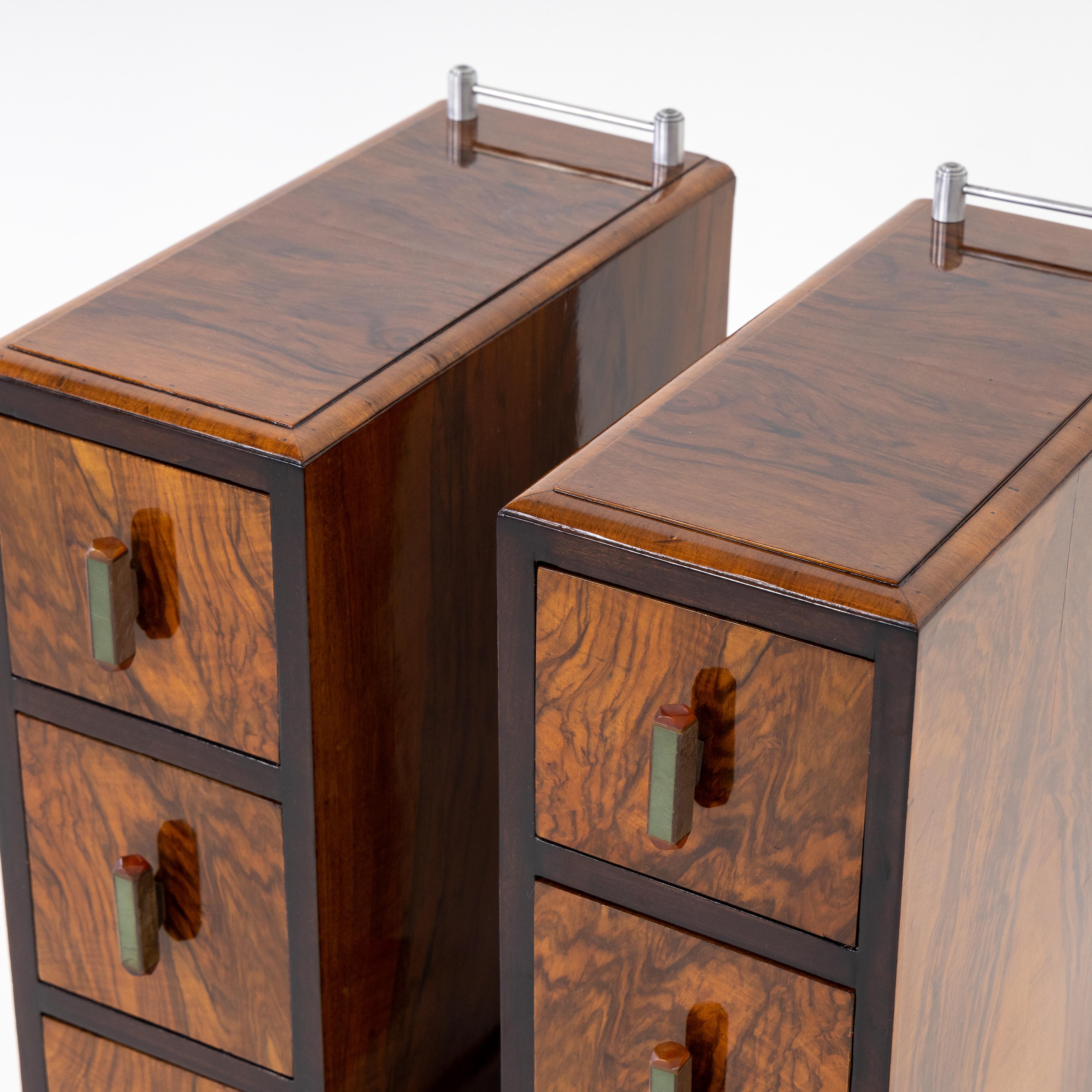Pair of narrow nightstands with three drawers and a short chromed gallery each, veneered in walnut.