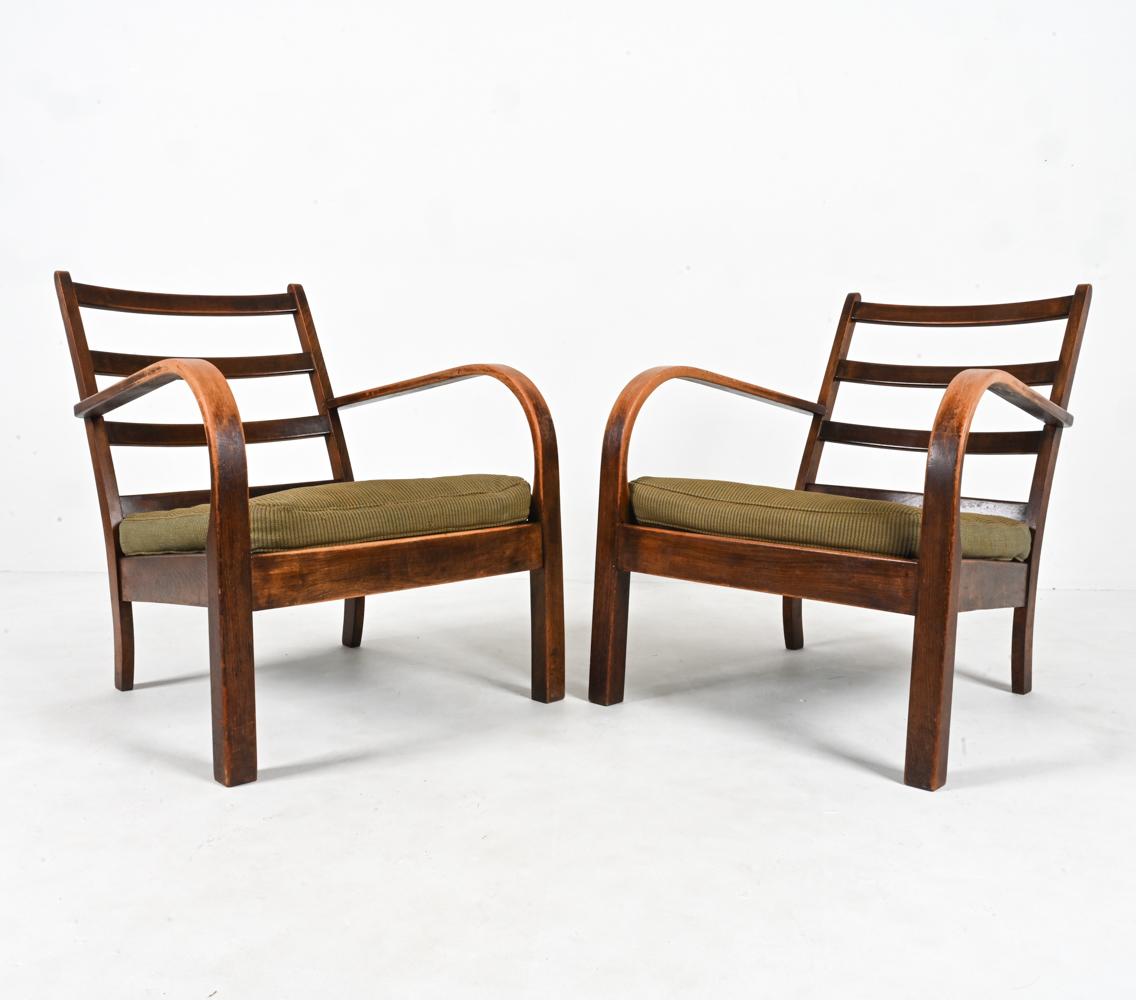 Elevate your space with this rare and exquisite pair of Art Deco open-arm lounge chairs, attributed to the iconic designer Frits Schlegel for Fritz Hansen and produced in Denmark during the 1940s. These chairs are a true testament to the timeless